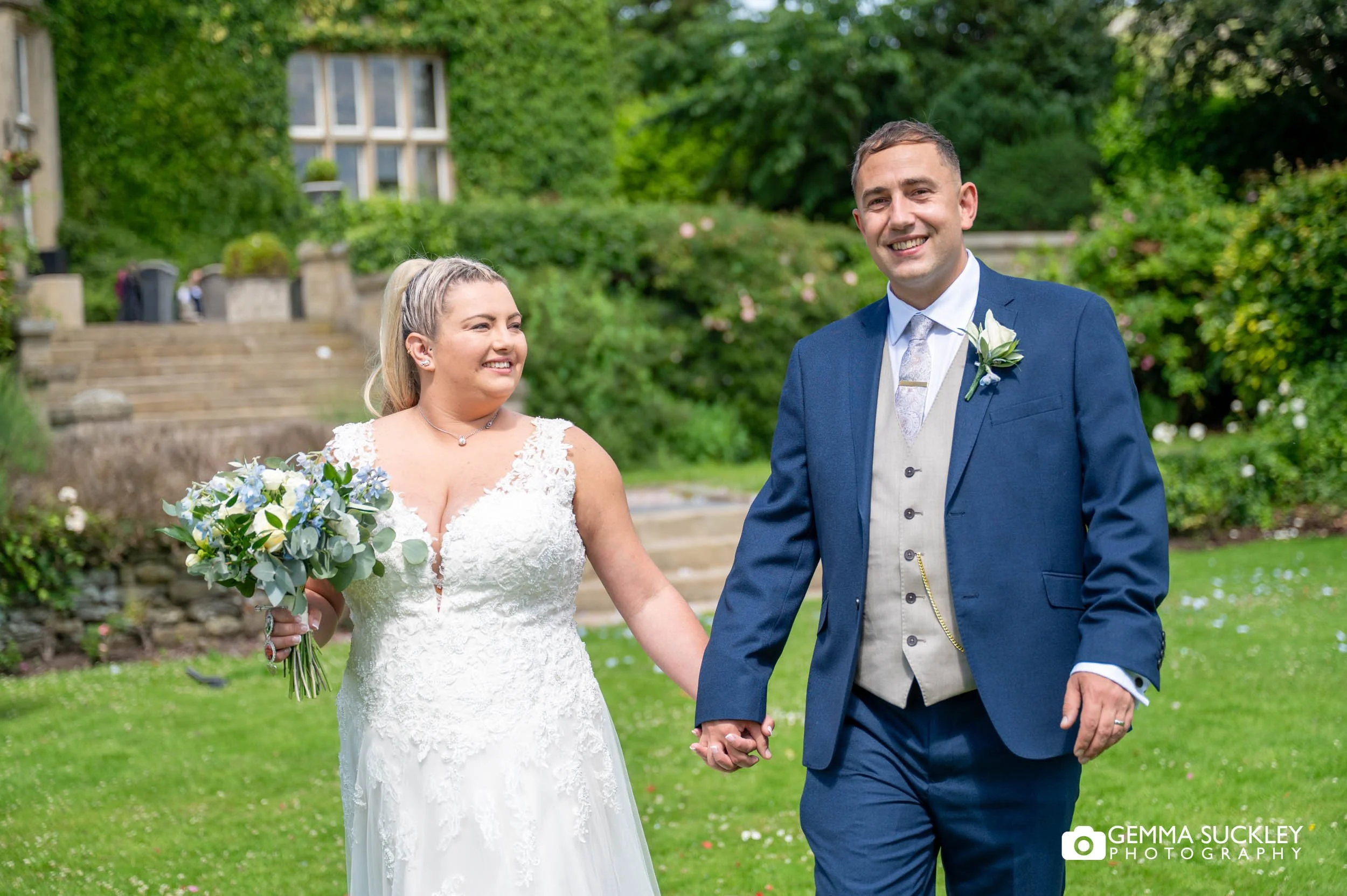 Newlyweds walking hand in hand through the grounds of Falcon Manor
