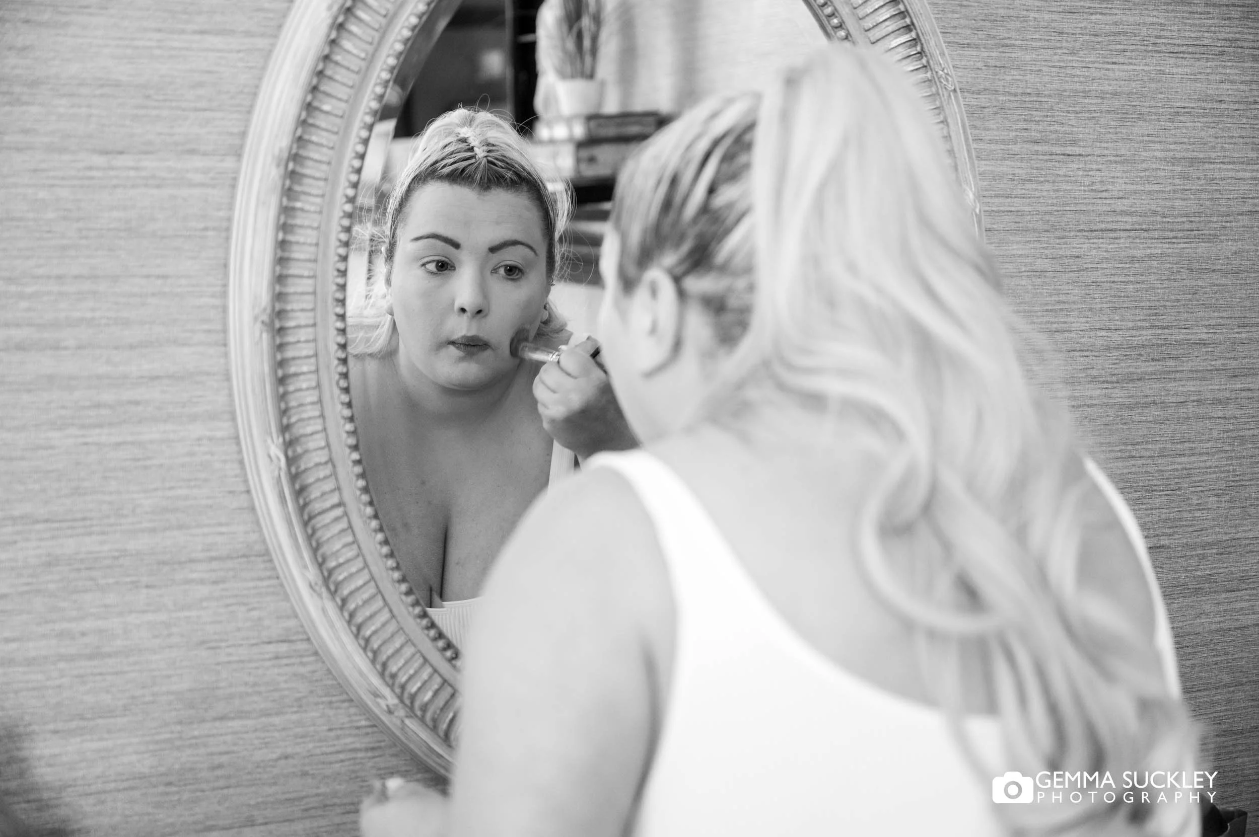 bride applying makeup in the mirror