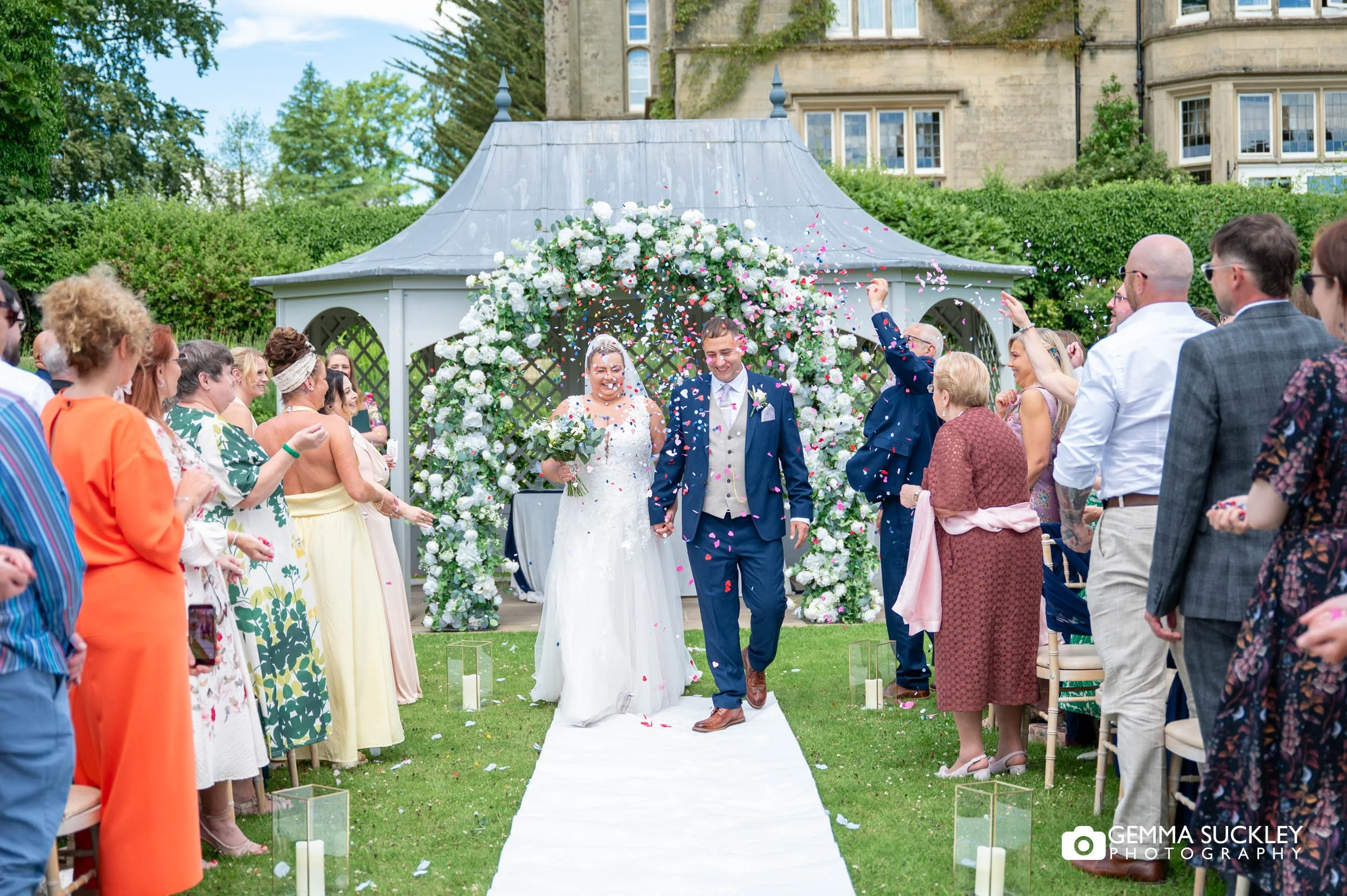 Bride and groom walking through a confetti tunnel