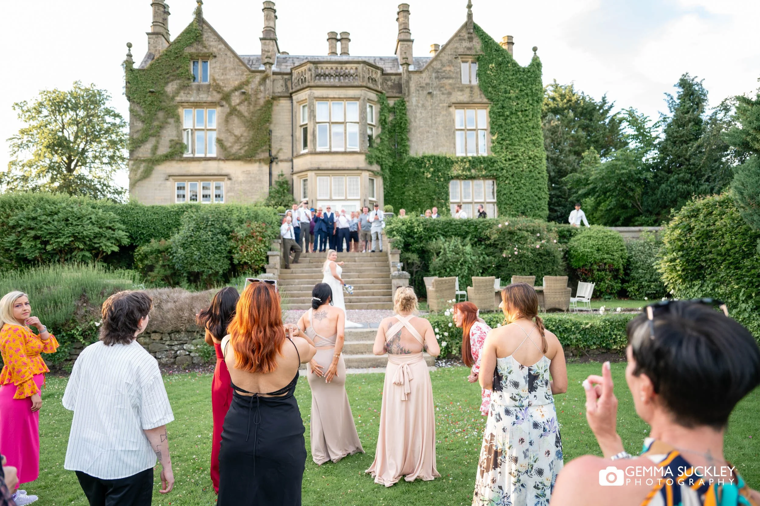 wedding guests outside the manor waiting to catch the bouquet