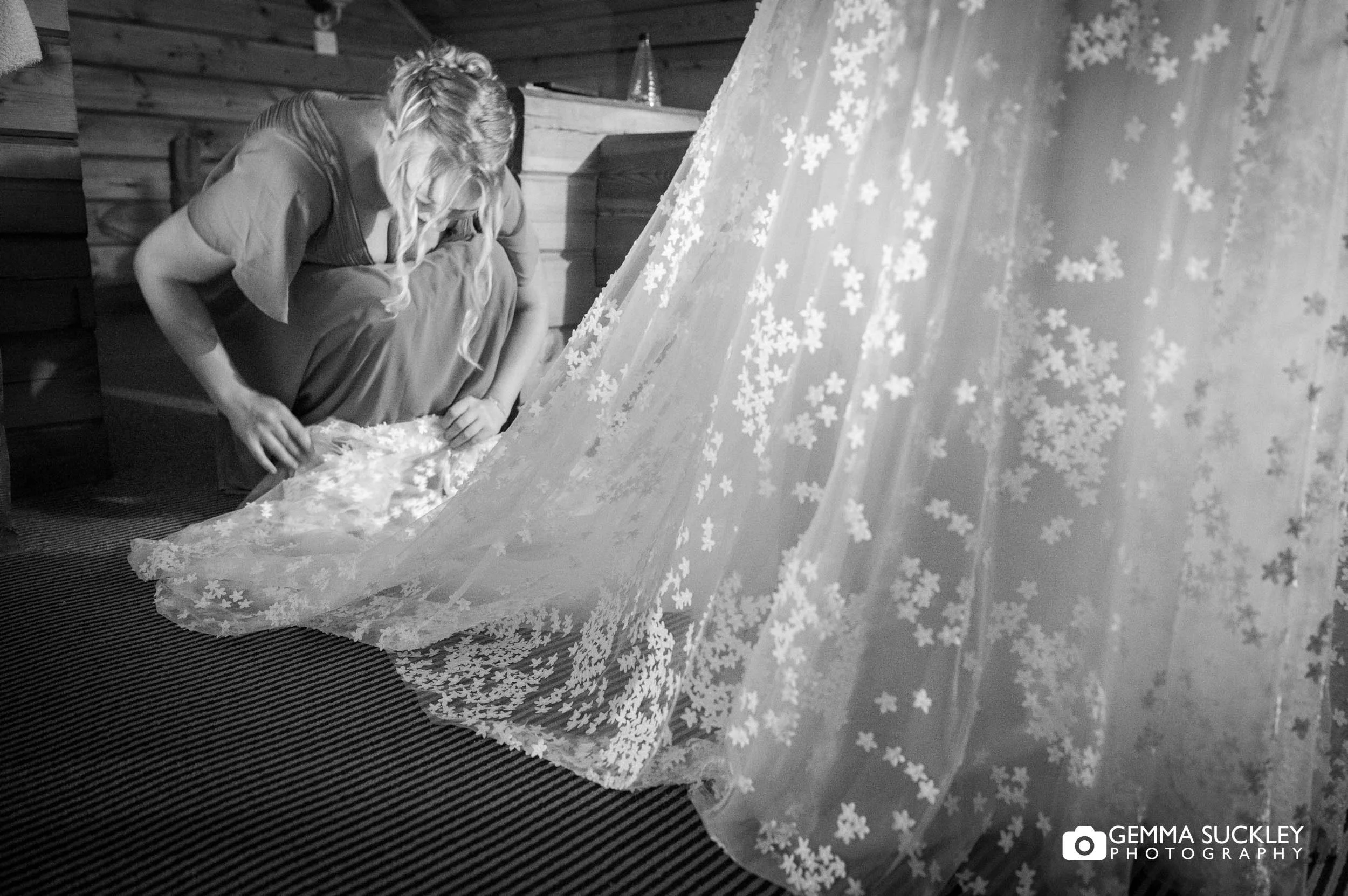 bridesmaid fanning out the brides dress 