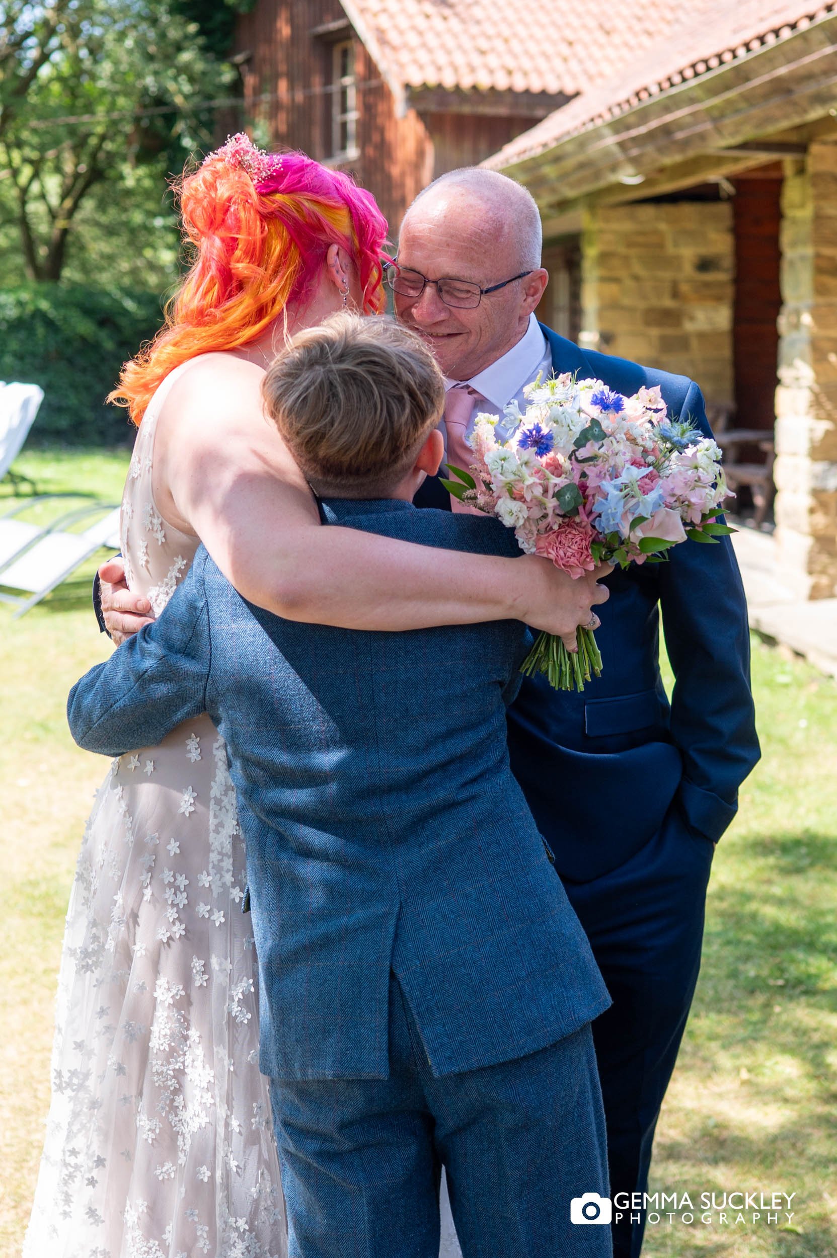 bride hugging her dad and son