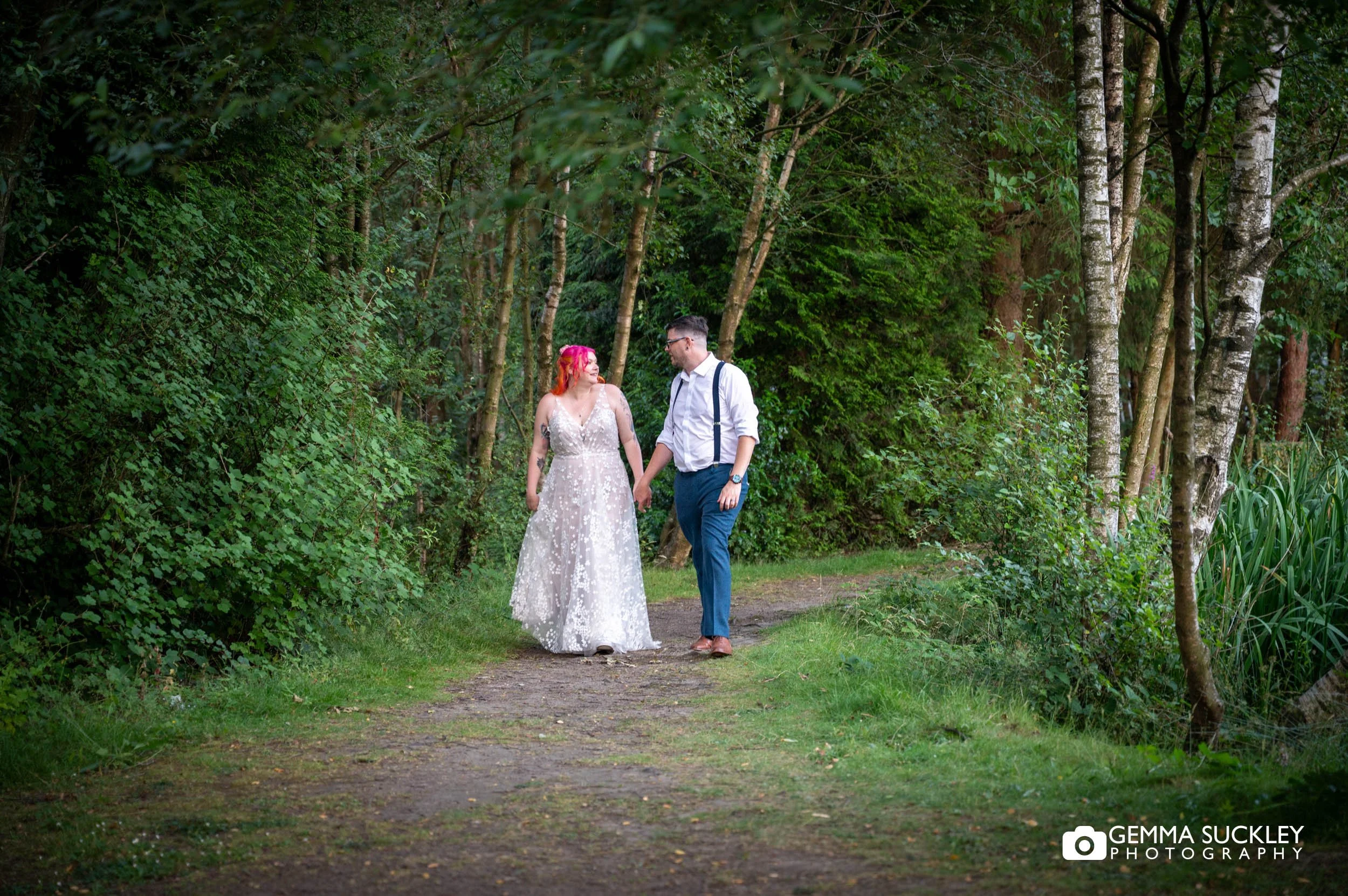 Bride and groom walking together through the woodland