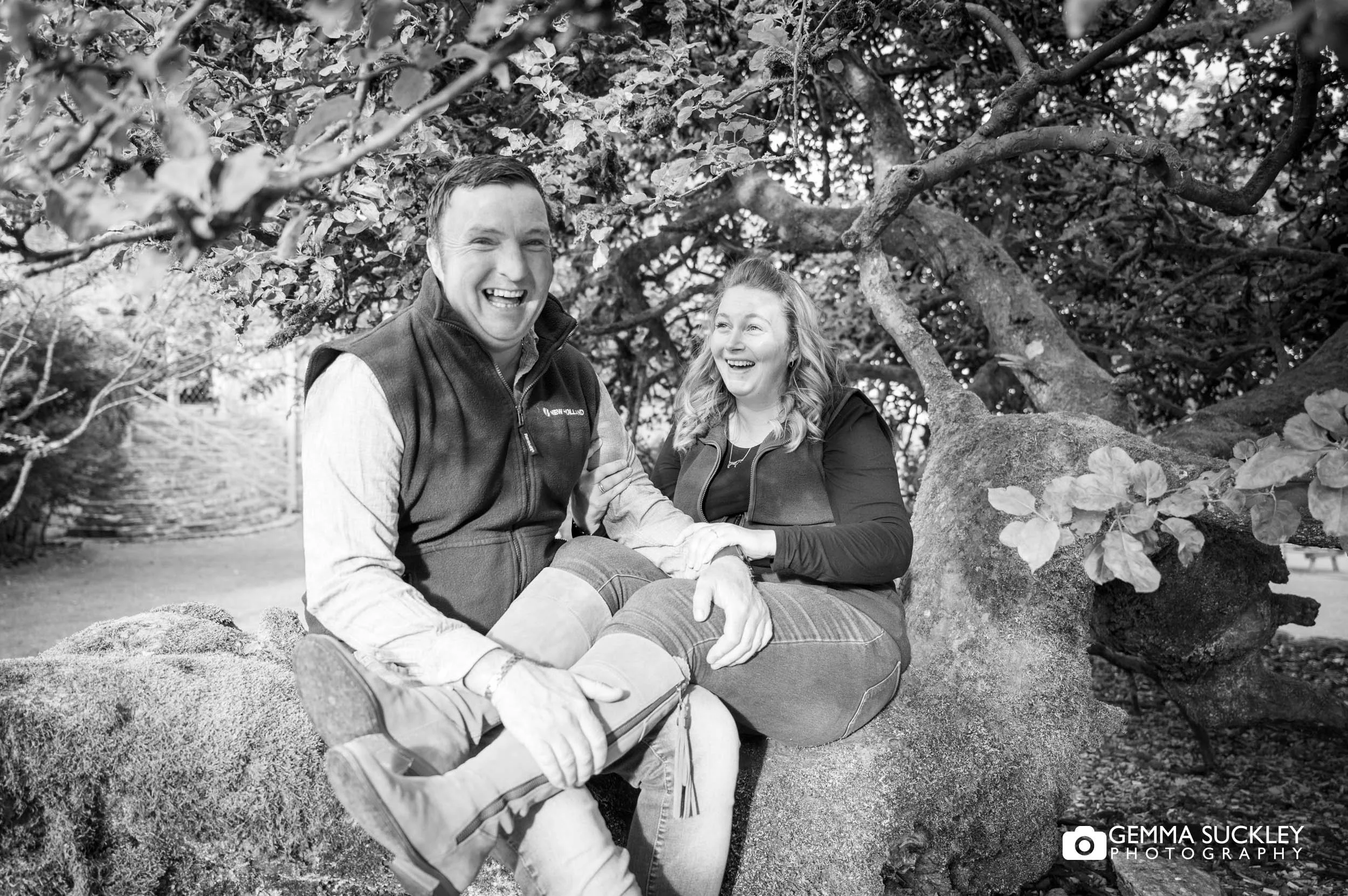 couple laughing beneath mature trees.