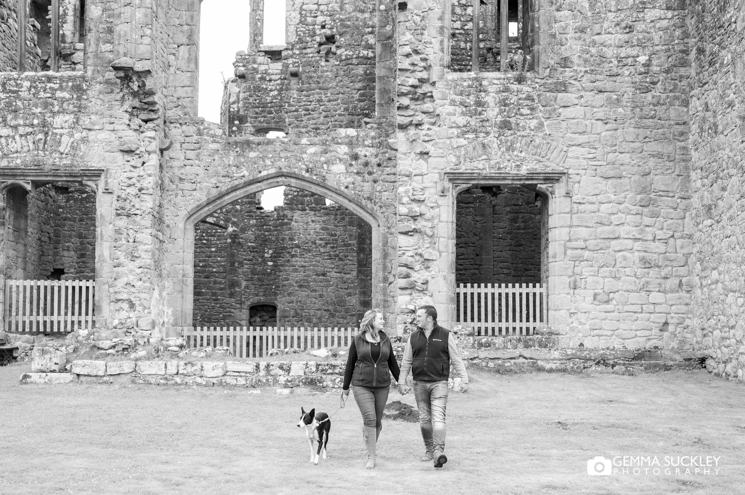 engaged couple with their dog in front of barden tower
