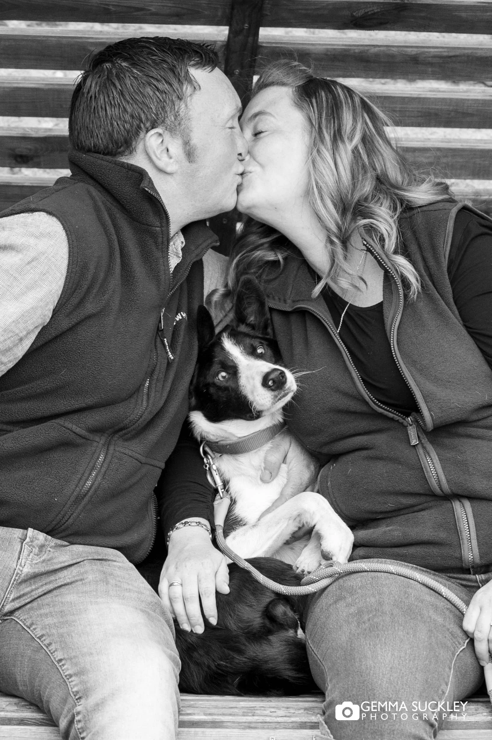 couple kissing with their dog between them