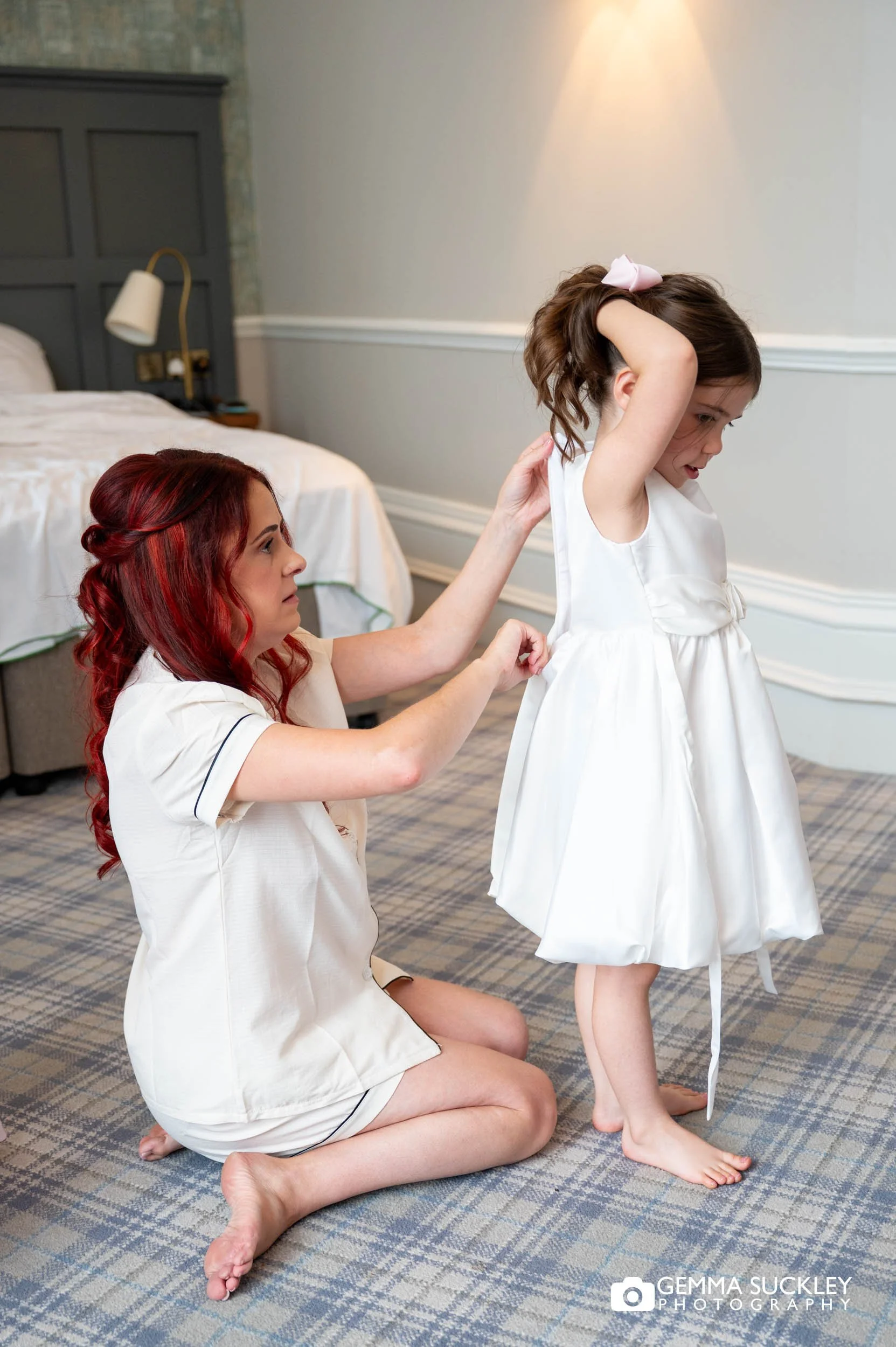 bride helping the flower girl into her dress