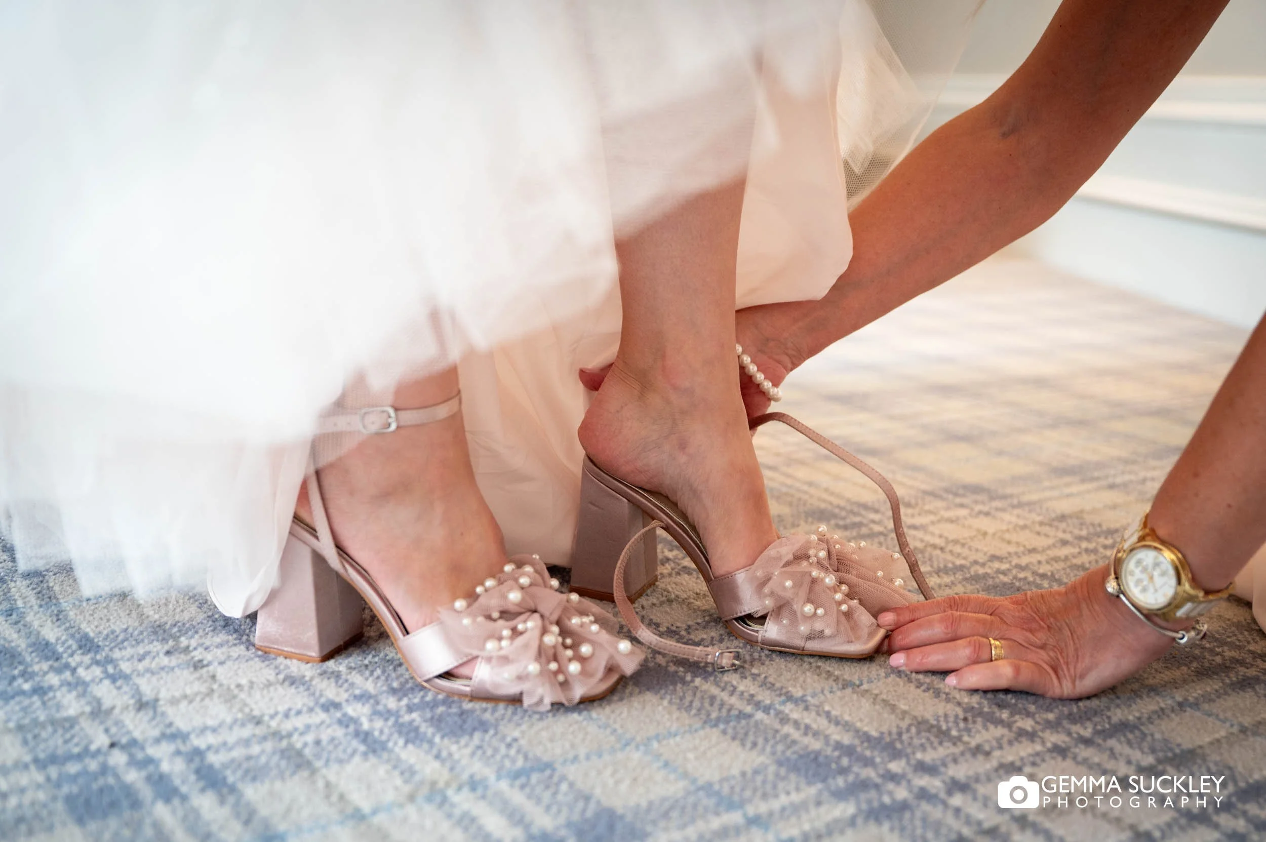 bride putting on bridal shoes