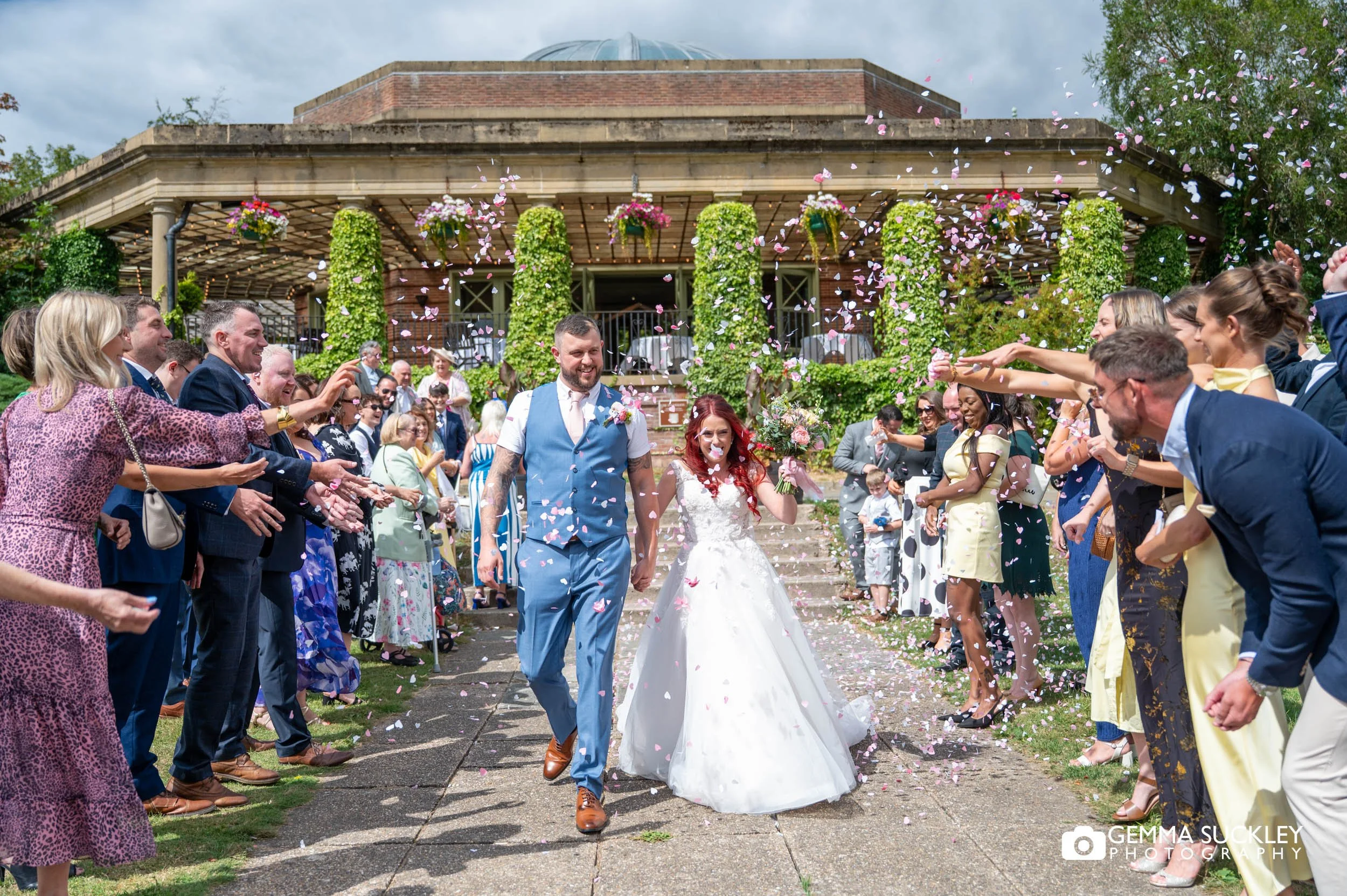 Bride and groom walking through confetti outside The Sun Pavilion