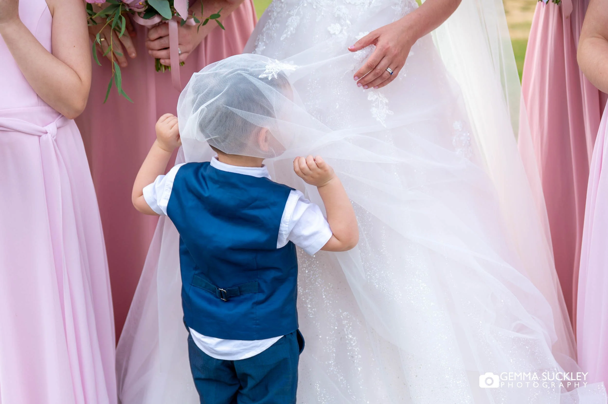 page boy hiding under the brides veil