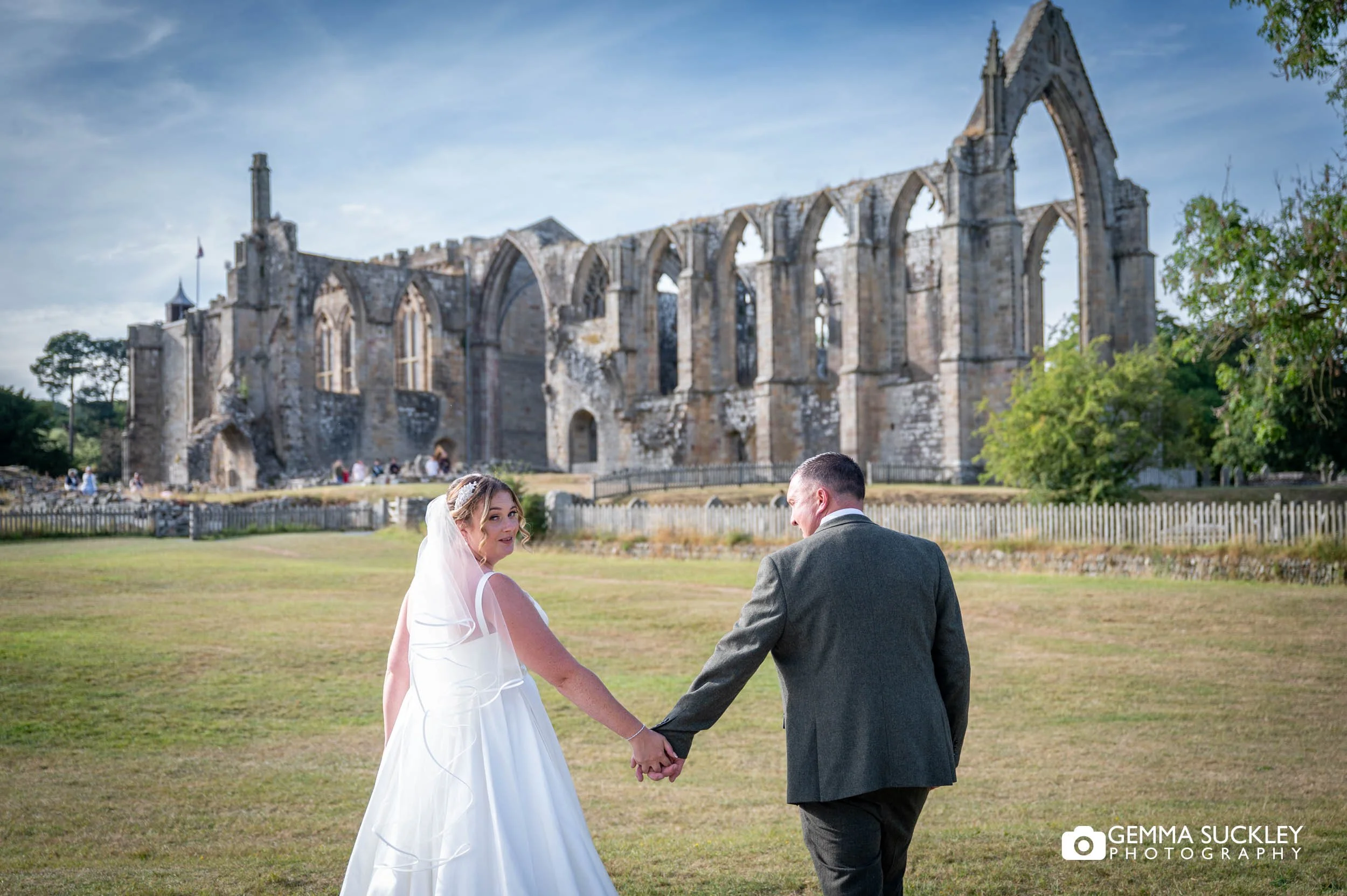 newly-weds walking in front of bolton abbey ruins