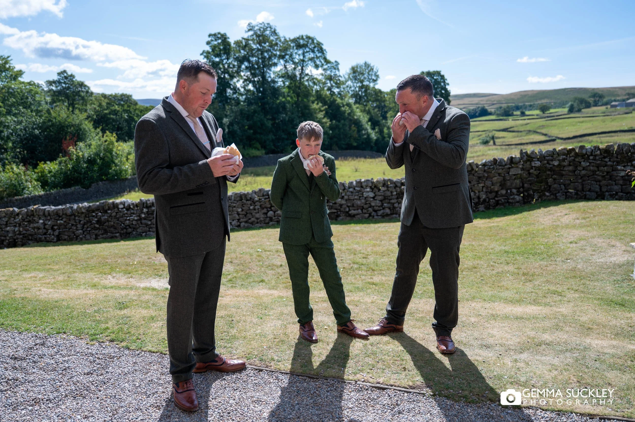 the groom and groomsmen having bacon sandwiches outside the priests house