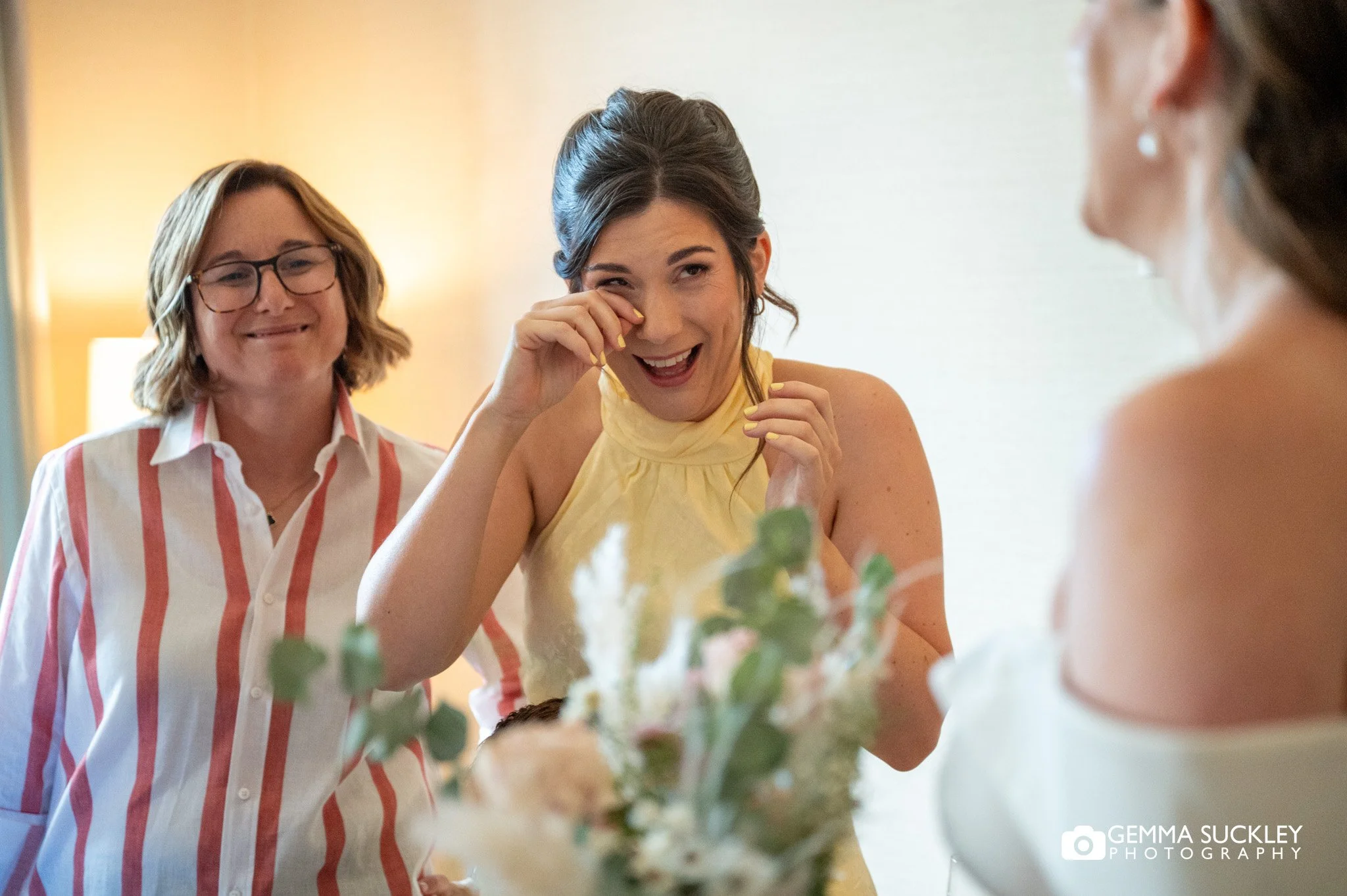 bridesmaid wiping away a tear after seeing the bride in her dress