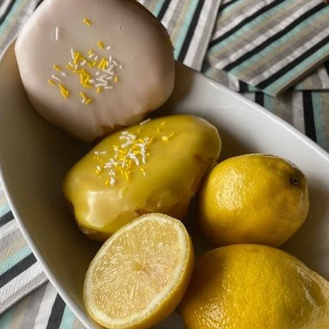 Can you spot the 2 Vanilla Lemon donuts in the picture?  One of them is nestled right next to real lemons...that's right! We now have Vanilla Lemon donuts in bright yellow fondant instead of white fondant.  You will still get the same tangy lemon pud