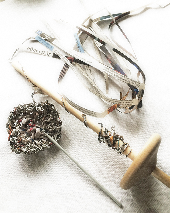 Spinning strips of newspaper with a drop spindle.