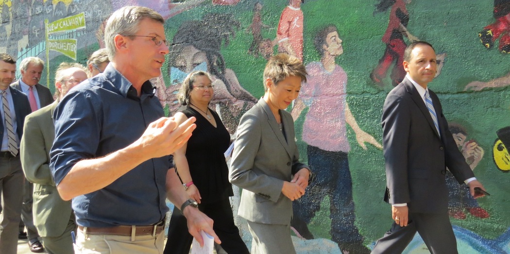 Harry Smith of the Fairmount Cultural Corridor initiative leads National Endowment for the Arts chairman Jane Chu on a tour of Uphams Corner. Janes Canales is beside her and San San Wong, both of the Barr Foundation, is behind them. Paul Grogan of the Boston Foundation is in the rear. (WBUR — Kristen Hagan/NEA)