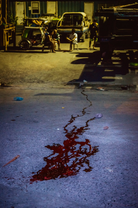 The blood and brains of Nikki Mercado, 27, trickle downhill into a gutter. Mercado's body was found dead with several gunshot wounds without any leads on a suspect. His death marks another case in the growing list of extrajudicial killings and forced disappearances that began during President Duterte's War on Drugs in 2016. NAVOTAS, MANILA. 2018.