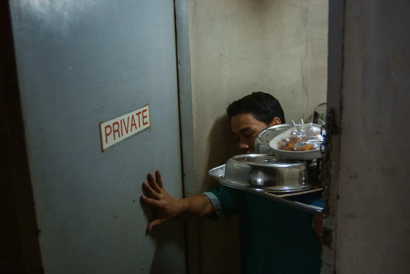 A waiter enters the service entrance into the penthouse of the Manila Manor Hotel. MALATE, MANILA. 2007.