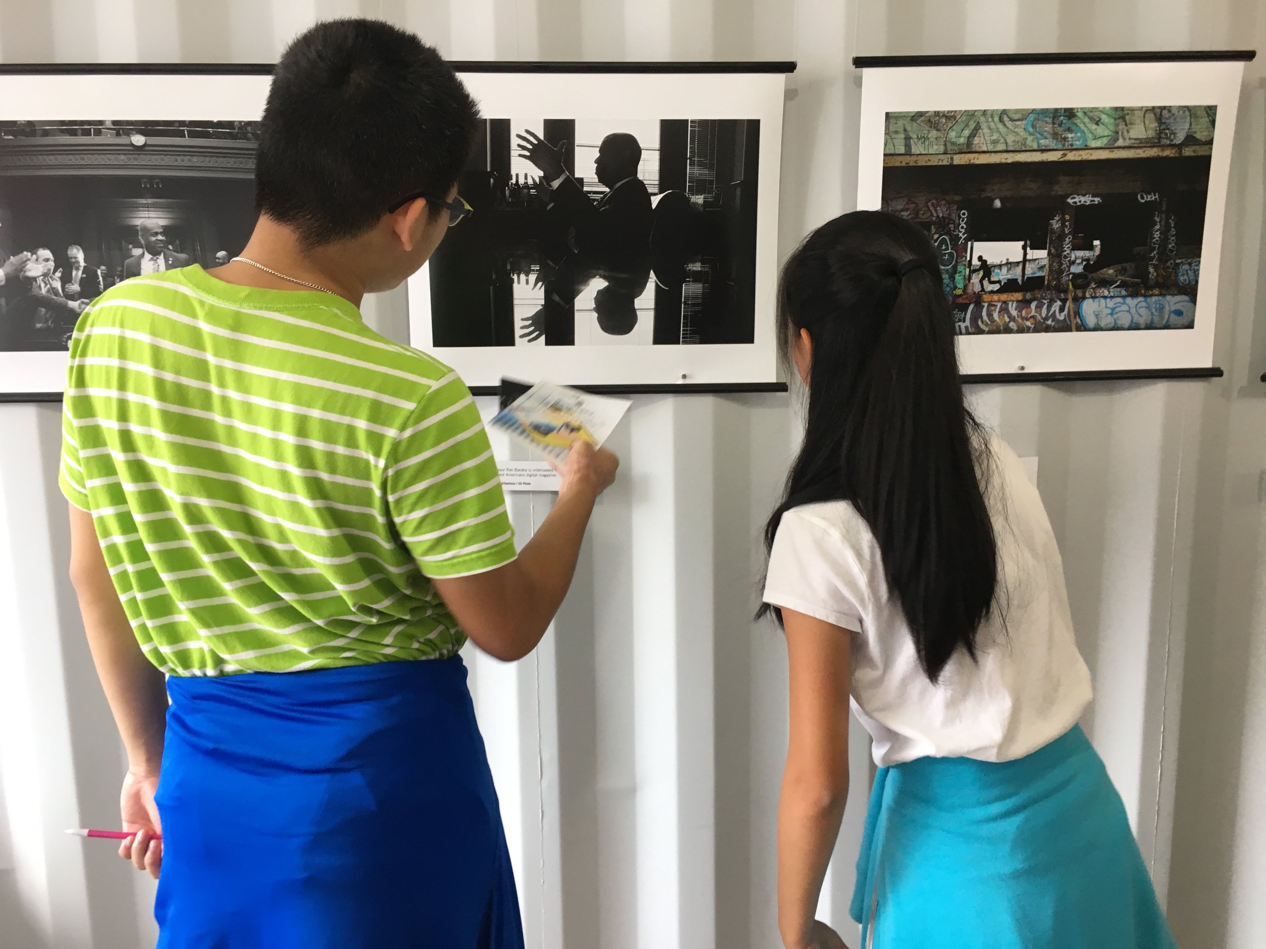  Students examine photos in the Newest Americans exhibit during Photoville's Education Day. Over 500 middle and high school students visited the photo village for an inside look at the exhibitions, artists and curators.&nbsp;(Photo by Julie Winokur) 
