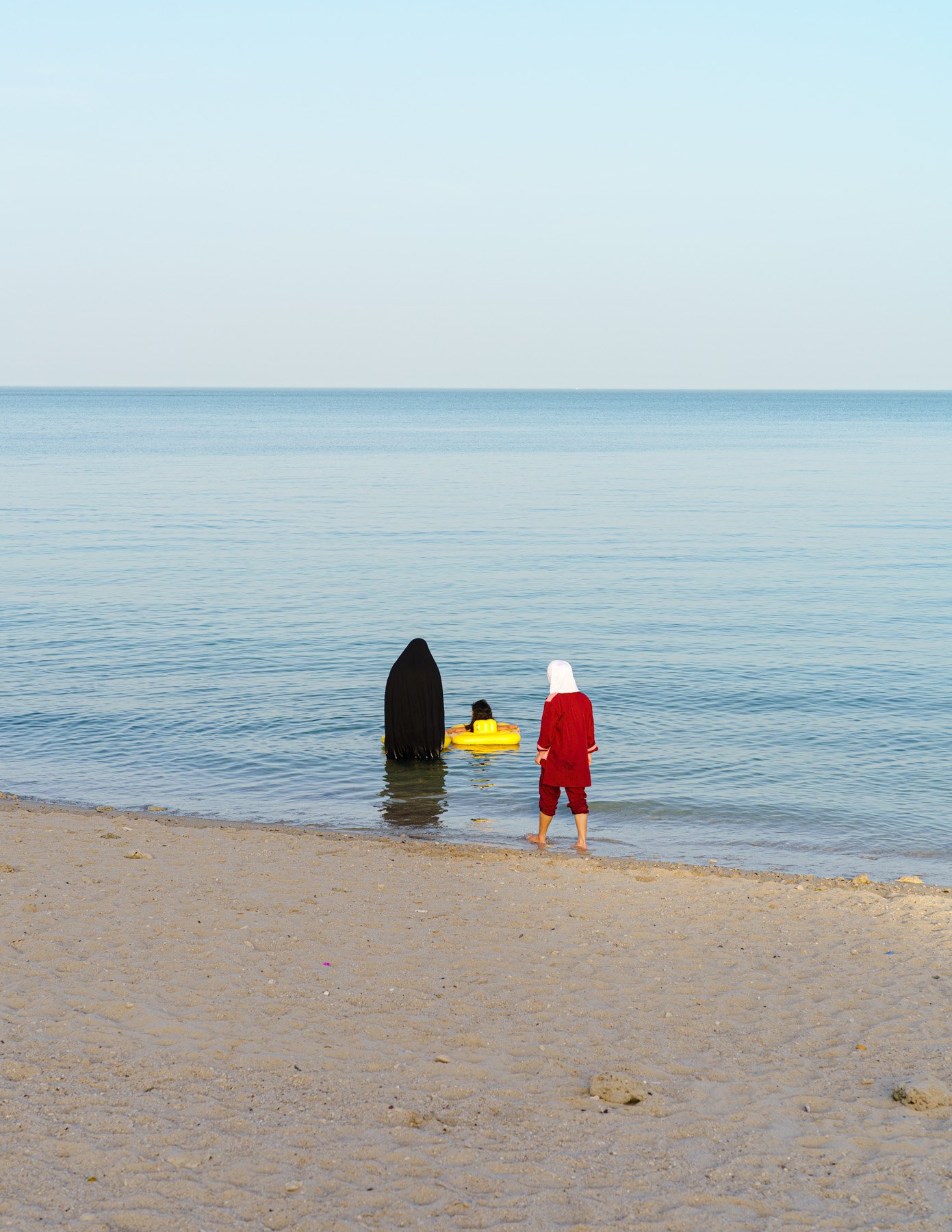  A mother and her maid look over their child.   Salmiya Beach, Kuwait. 2021 
