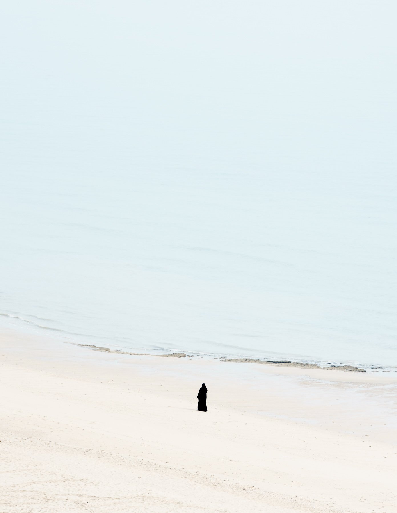  A woman walks along the beach on a misty autumn morning in Kuwait.   Salmiya, Kuwait. 2021 