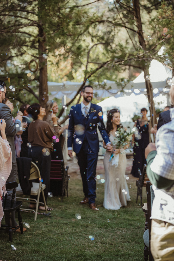 Nevada City wedding bride and groom walking down the aisle as guests blow bubbles photo