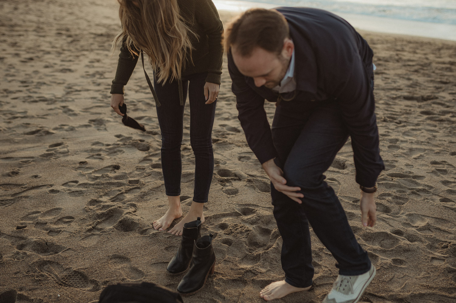 San Francisco engagement couple taking off their shoes at Baker Beach photo