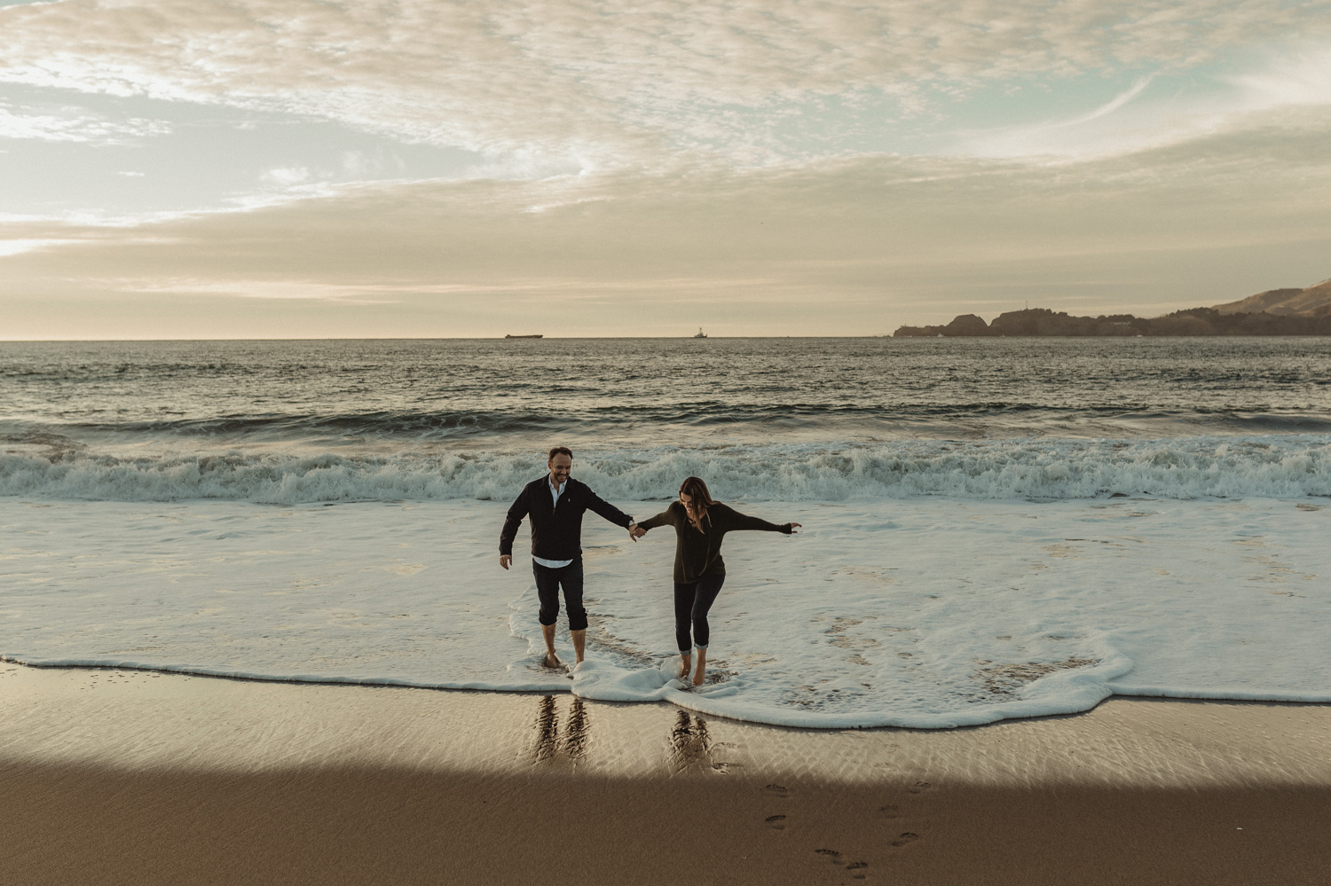 San Francisco engagement couple walking by the shore at Baker Beach photo