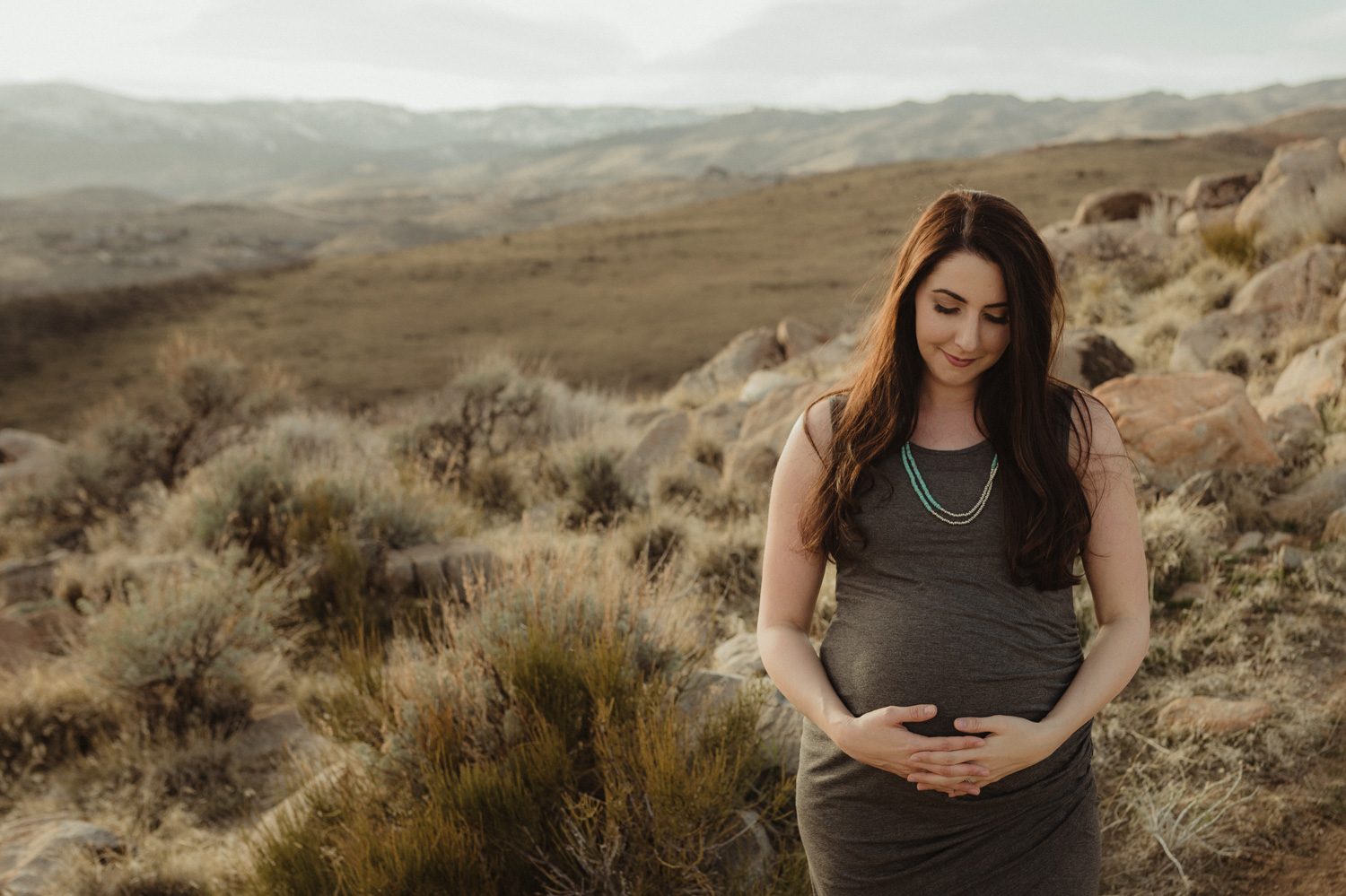Desert maternity session mom looking at her belly photo