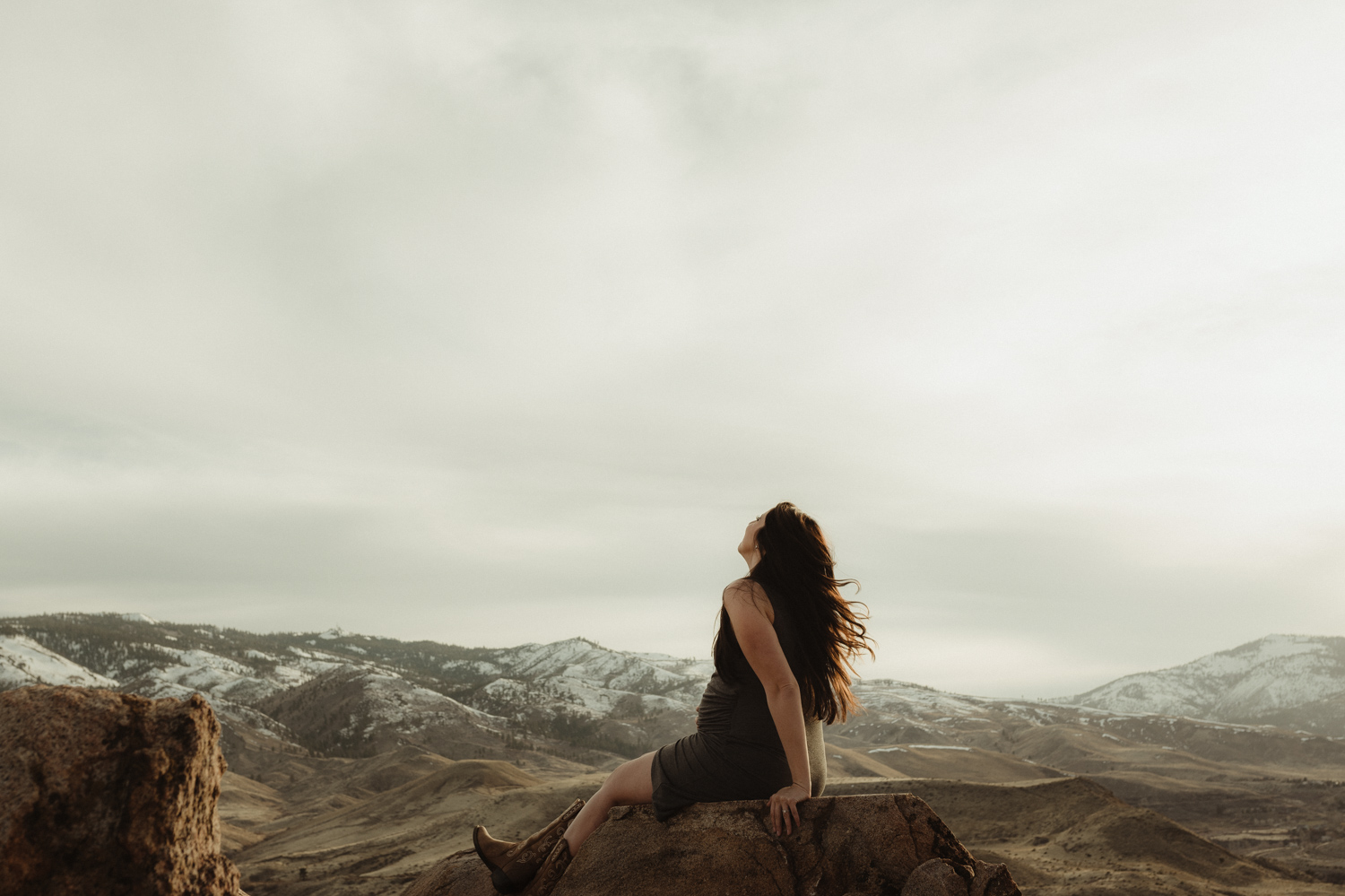 Desert maternity session mom sitting on a tall rock photo