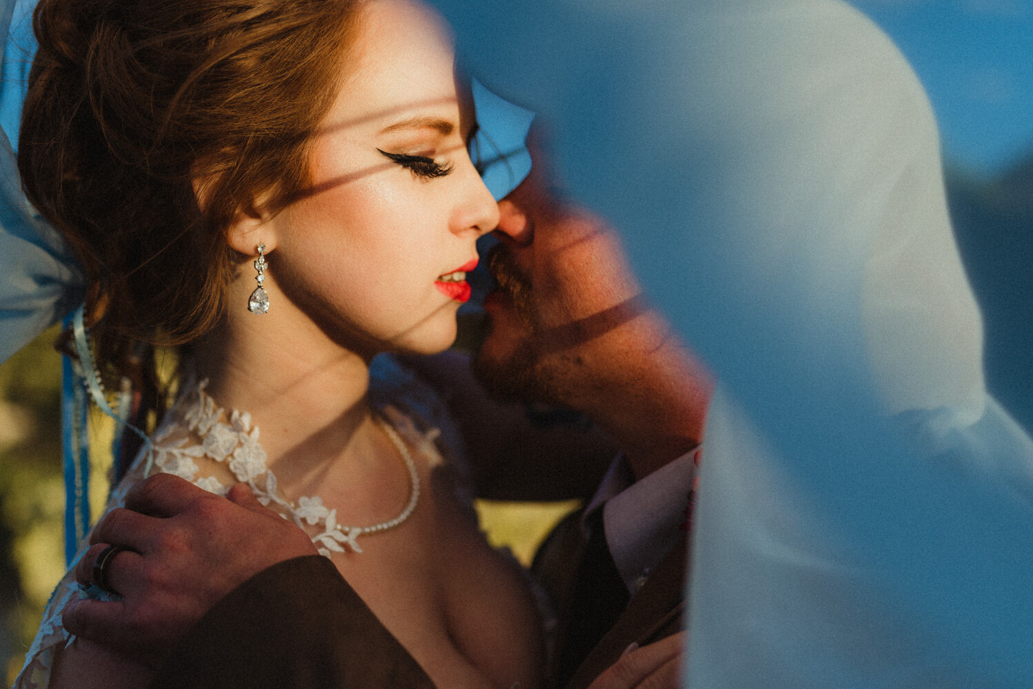 River School Farm Eclectic Wedding, couple kissing under brides blue veil 