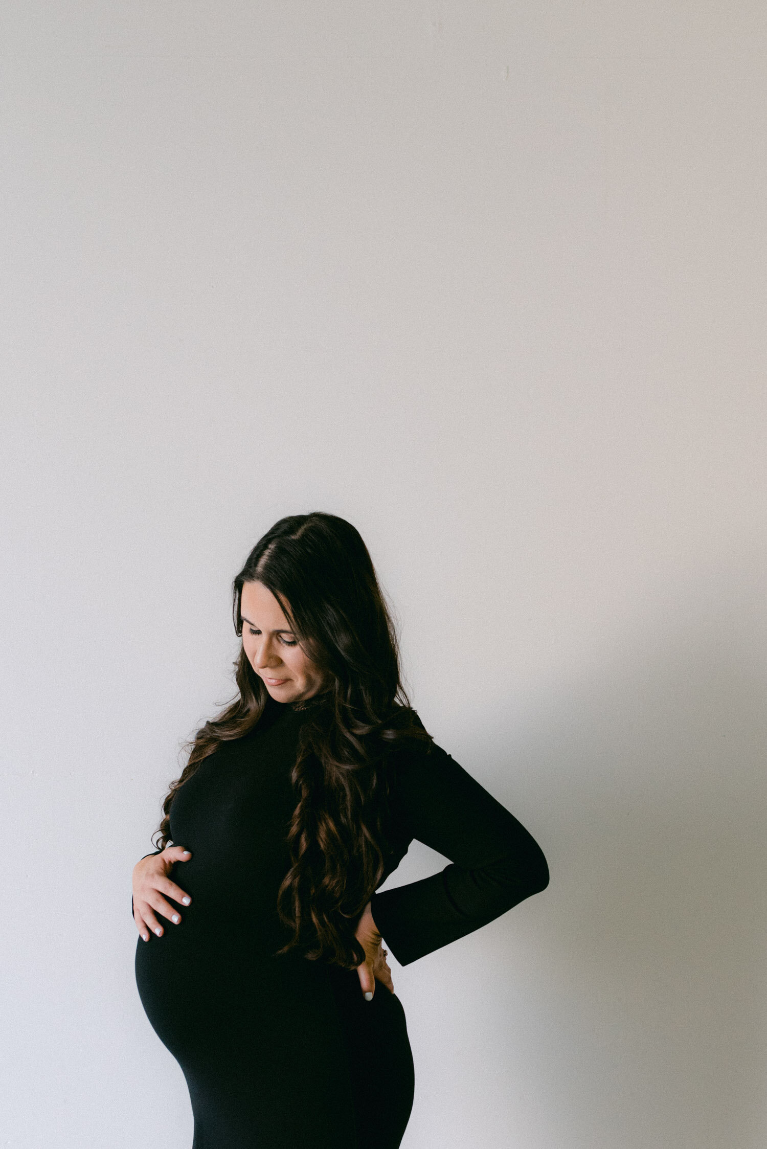 Studio Maternity Session in Reno, with a white background, photo of mom holding her belly. 