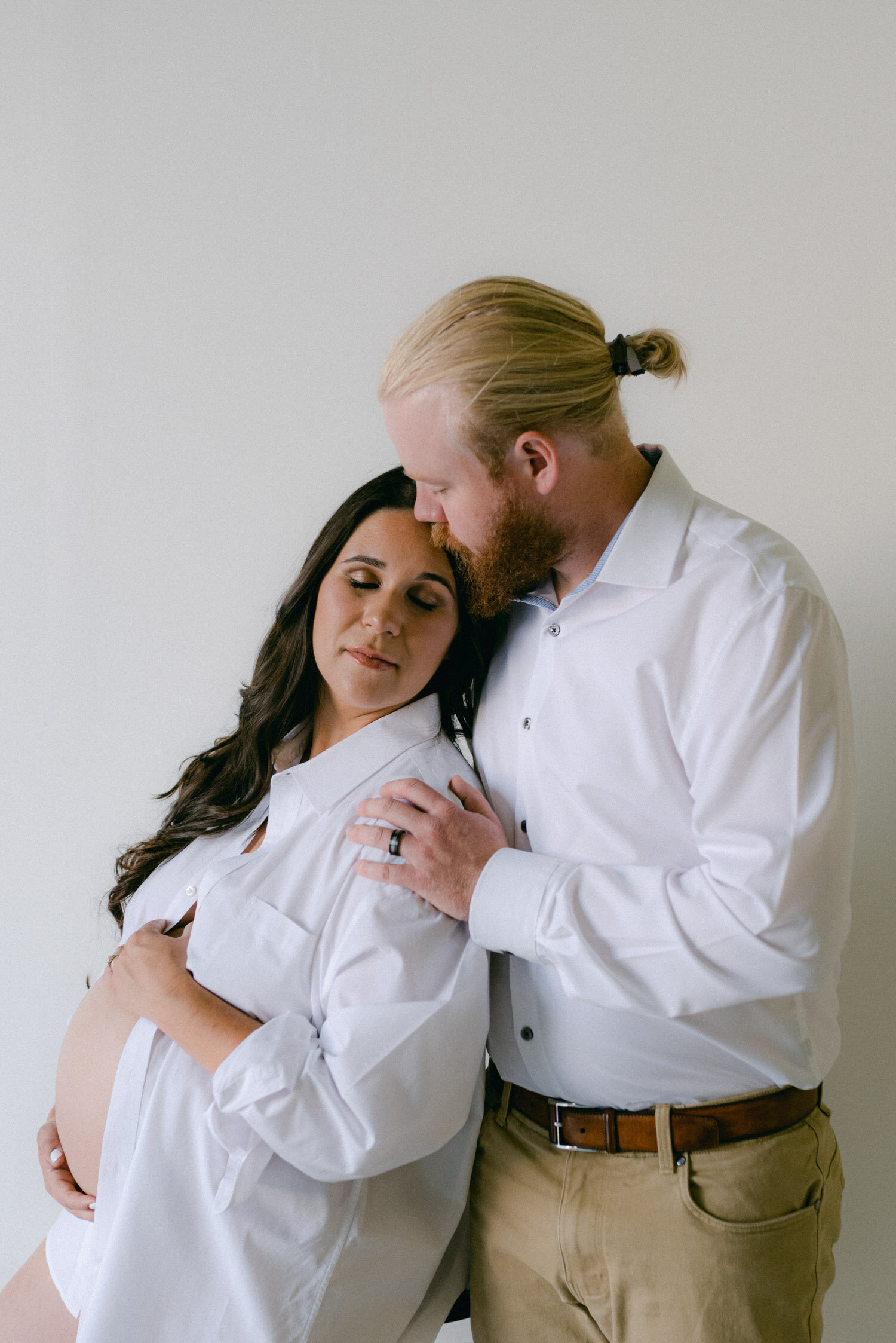 Studio Maternity Session in Reno, with a white background, photo of couple wearing white dress shirts