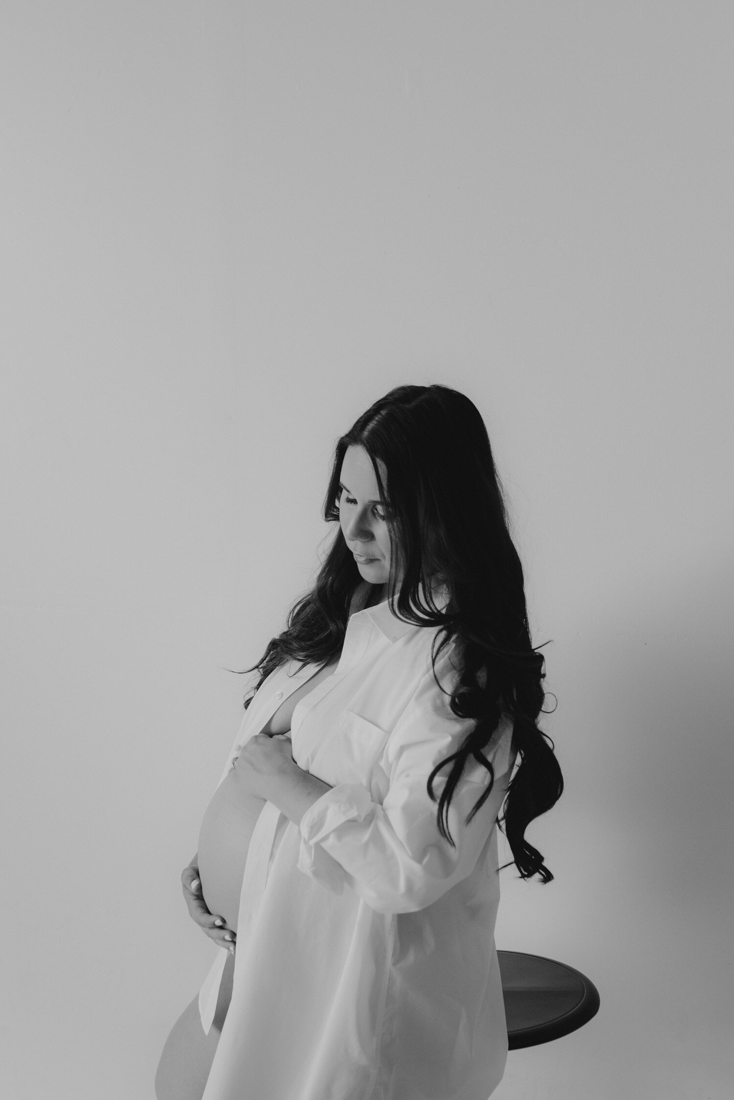 Studio Maternity Session in Reno, with a white background, photo of couple standing back to back for their studio session 