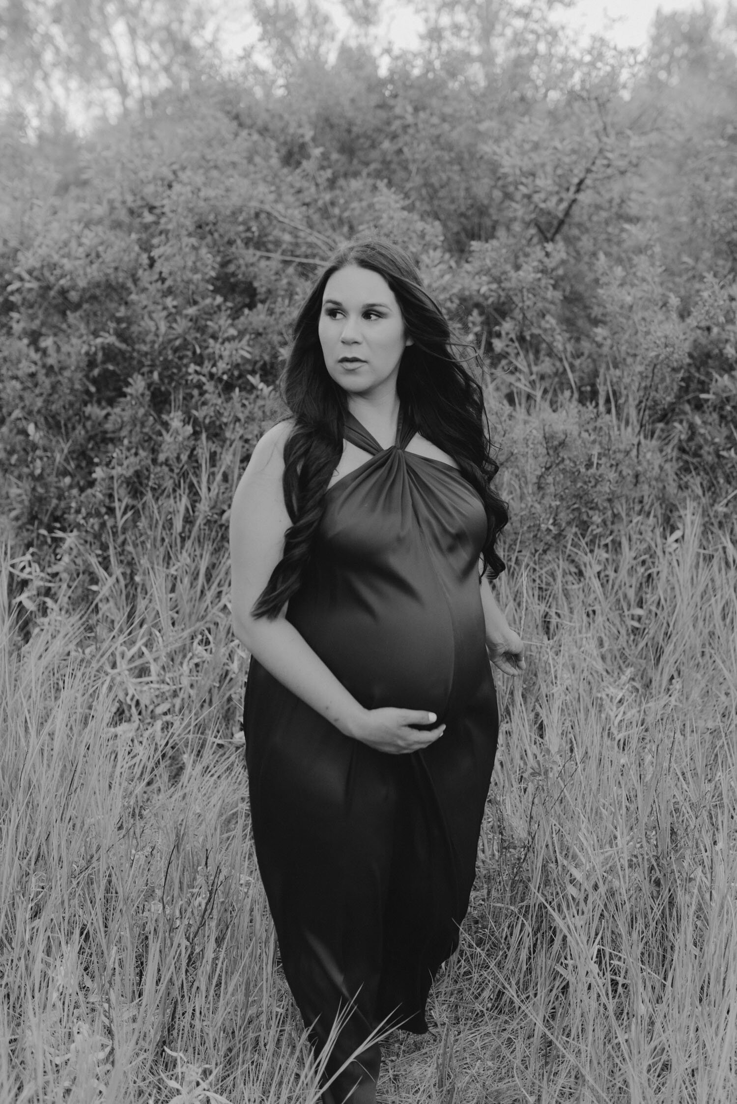 Maternity session in the meadows, mom to be wearing a red maternity gown and walking away