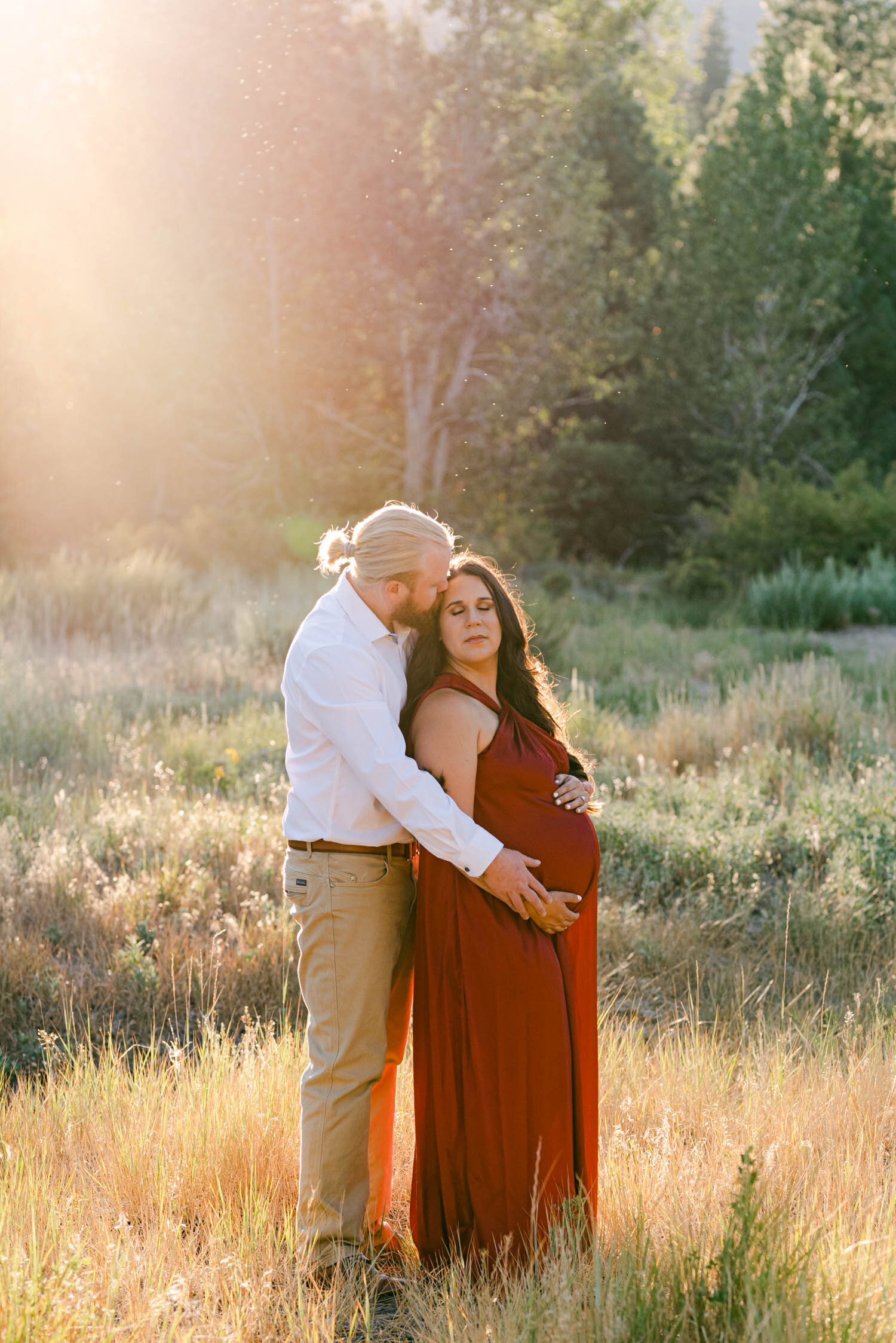Golden hour maternity session, mom to be is wearing a red gown from rent the runway