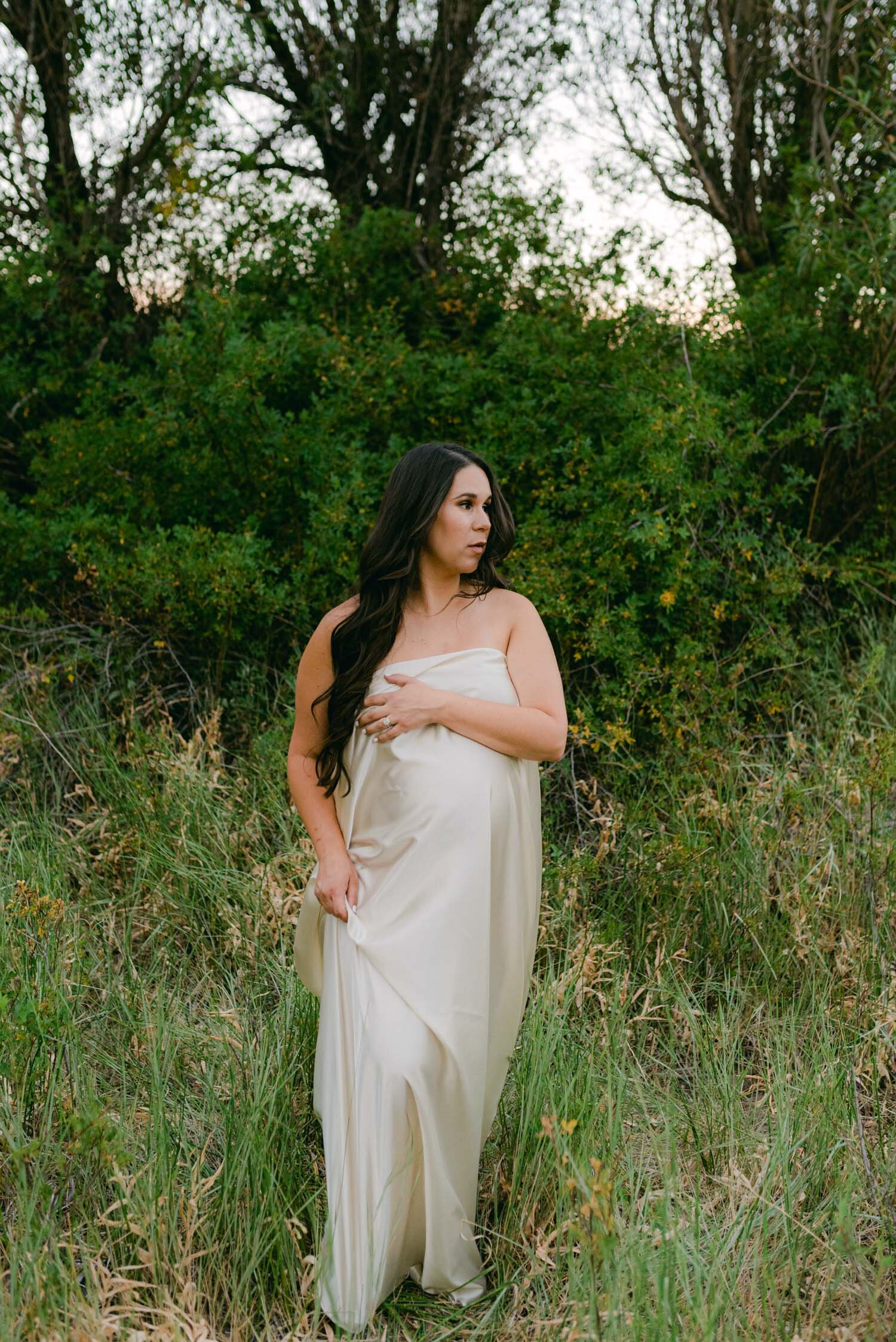 Maternity session in the meadows. Mom is draped in off white silk-like fabric