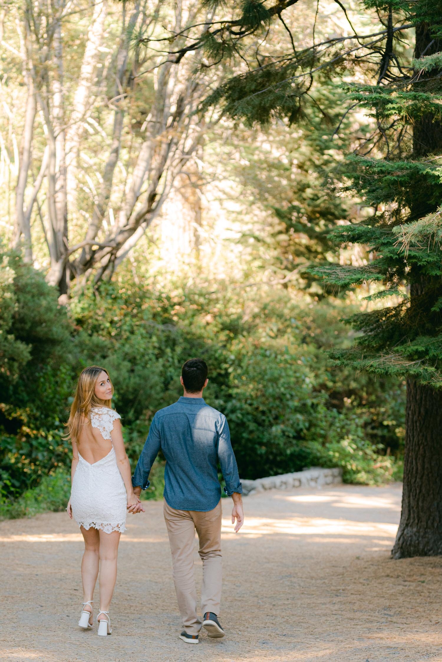 Emerald Bay engagement photoshoot, photo of a couple walking away and the girl looking over her shoulder