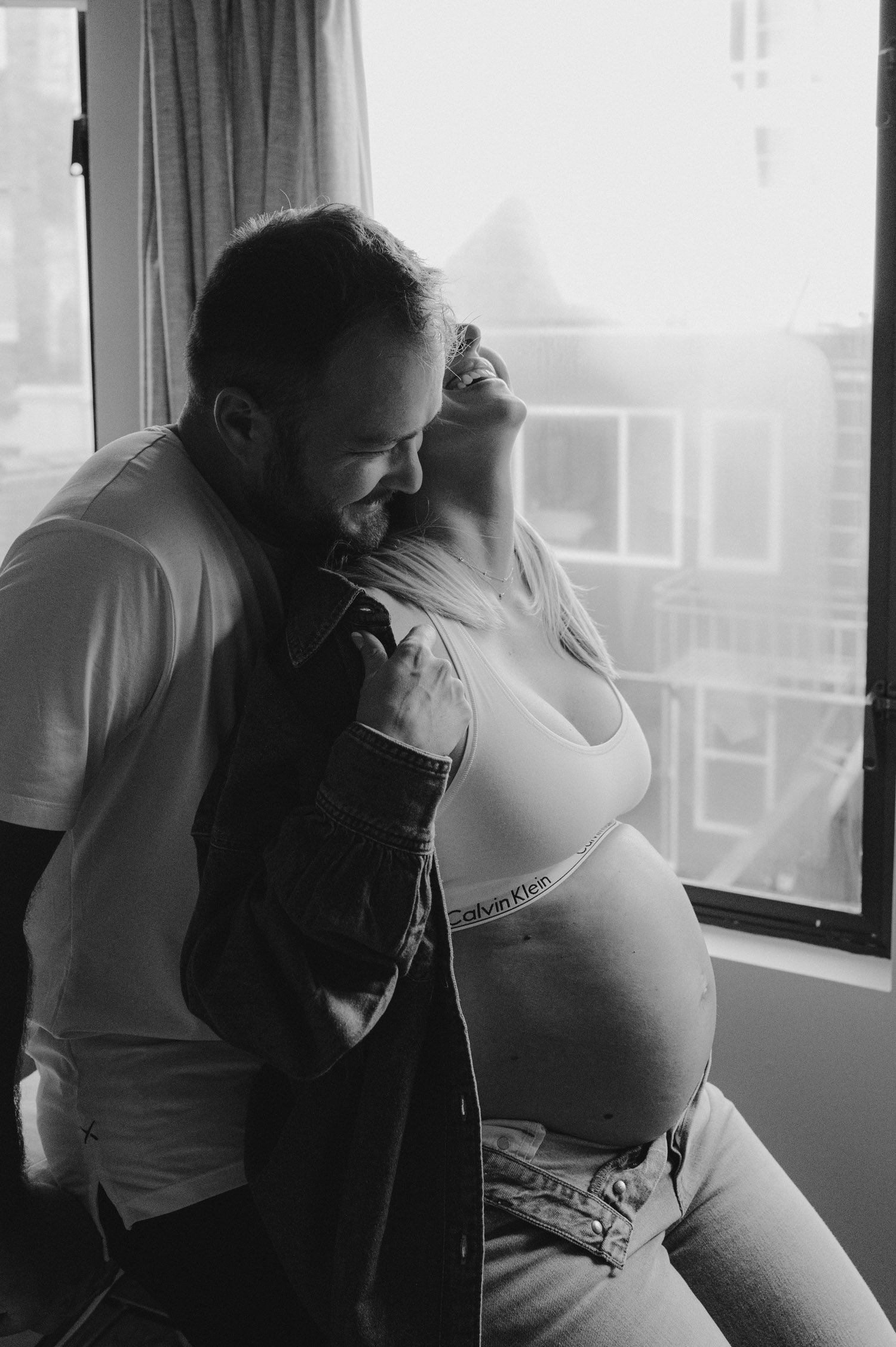 san francisco home maternity session, photo of mom-to-be and her husband cuddling by the window 