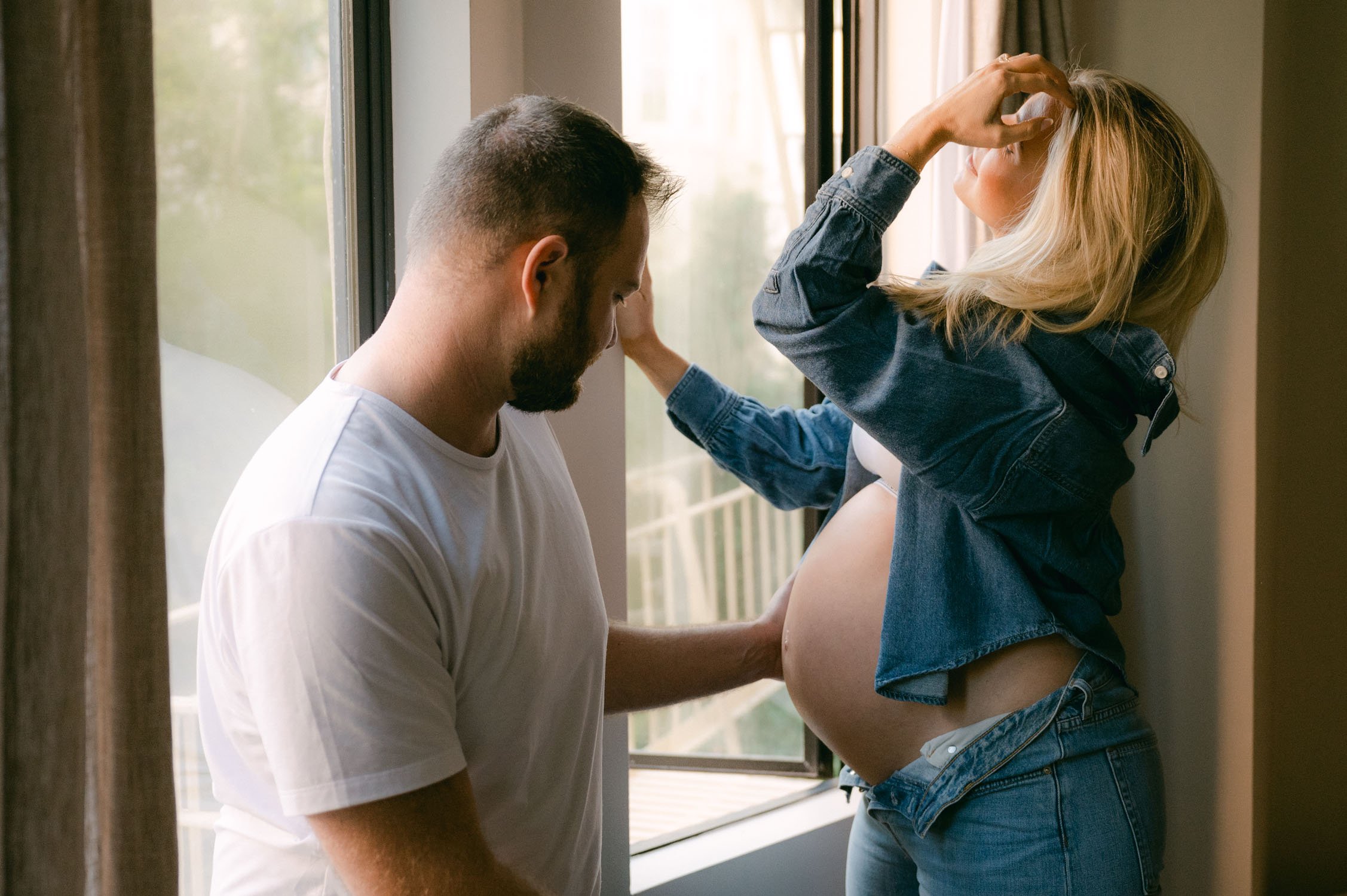 san francisco home maternity session, photo of mom-to-be wearing a jean jacket with a Calvin Klein sports bra