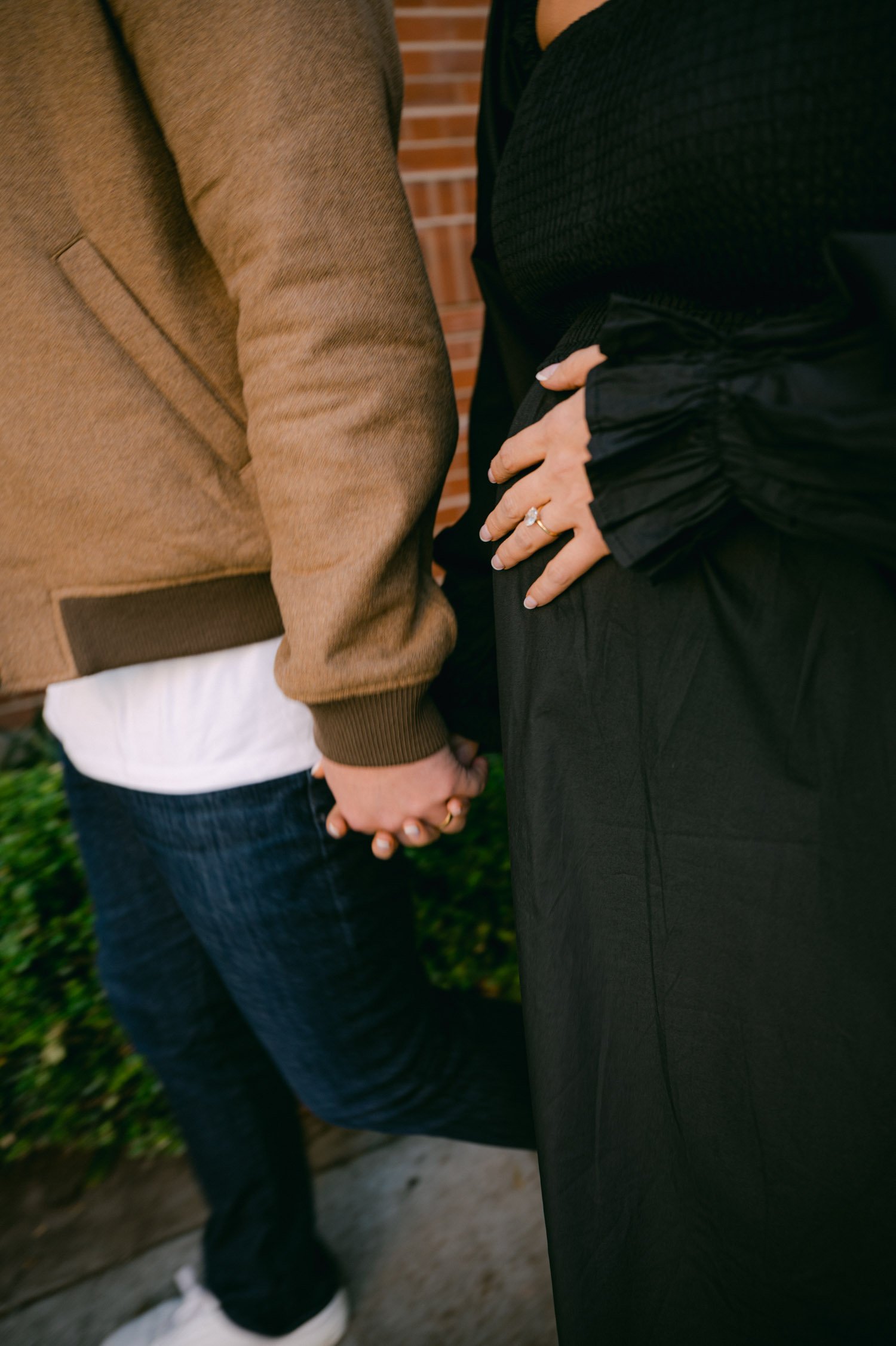 san francisco maternity session, photo of couple holding hands. mom is wearing a black dress with white tennis shoes and dad is wearing a tan jacket