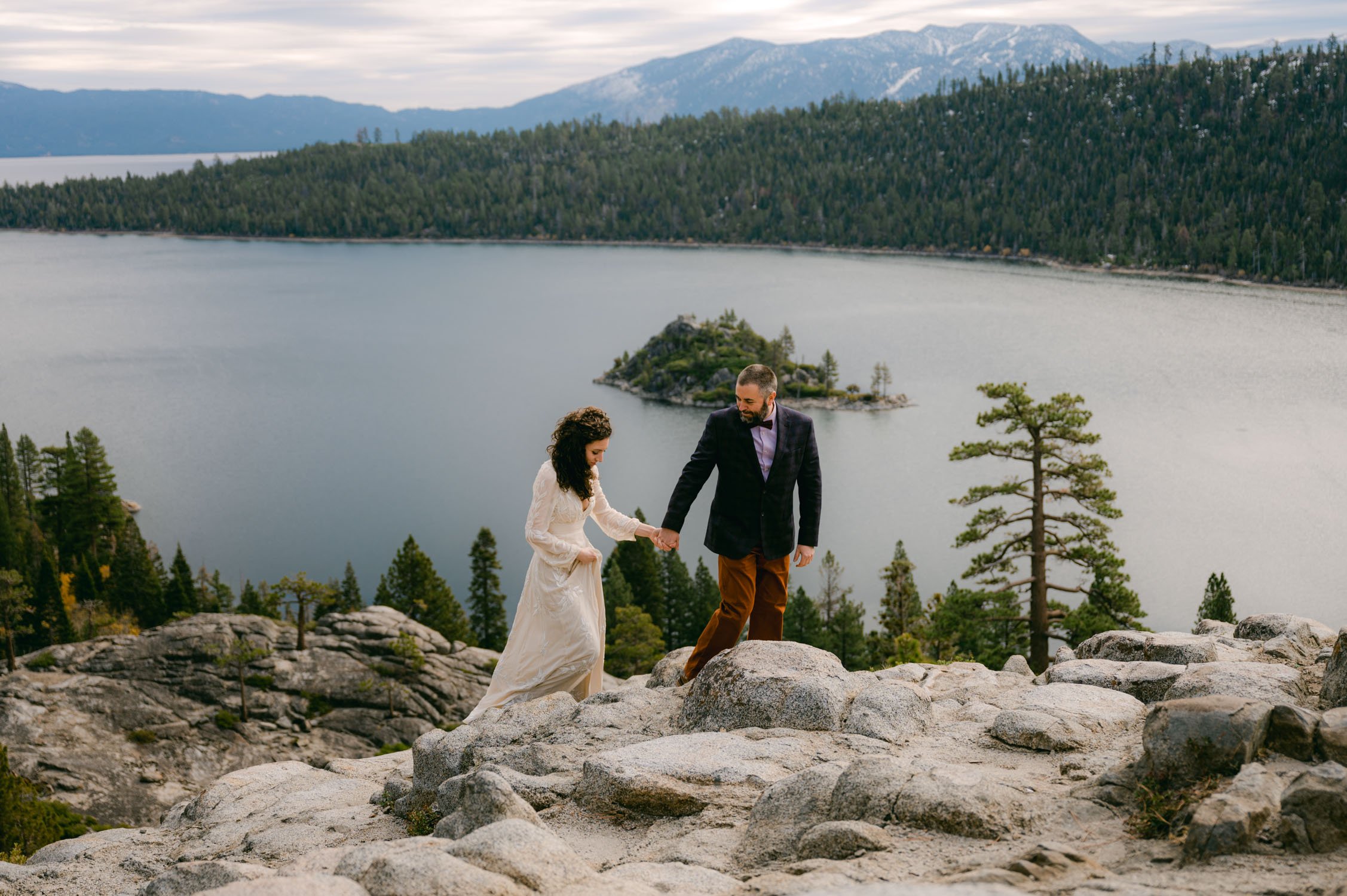  Emerald Bay Elopement Photographer, photo of a couple holding hands and walking at an overlook 