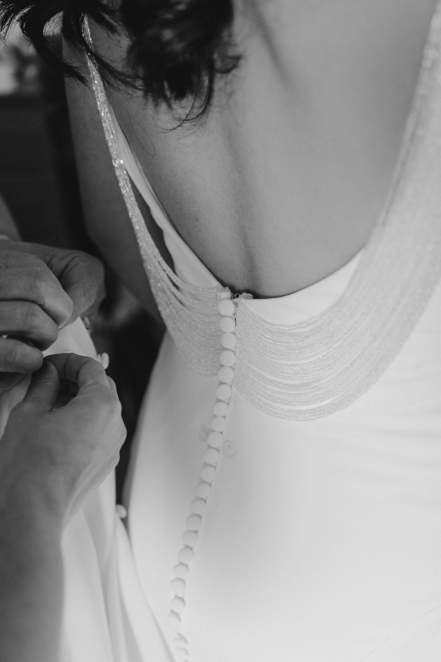 Tahoe Bleu Wave Wedding photo of bride putting on her dress with a hanging gem detail on the back