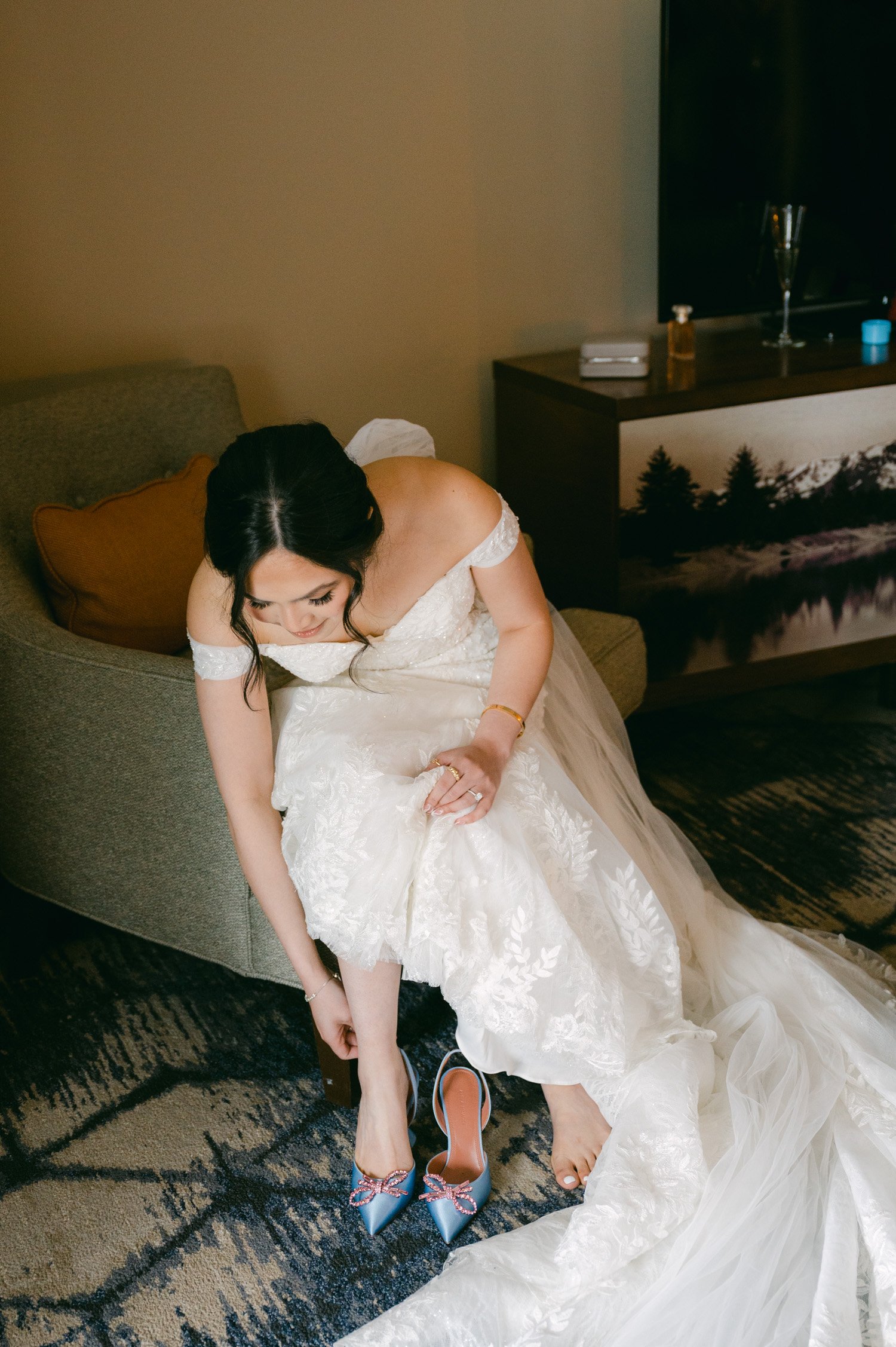 Edgewood Wedding photos, photo of bride putting on her Amina Muaddi wedding shoes (blue with a pink crystal bow)