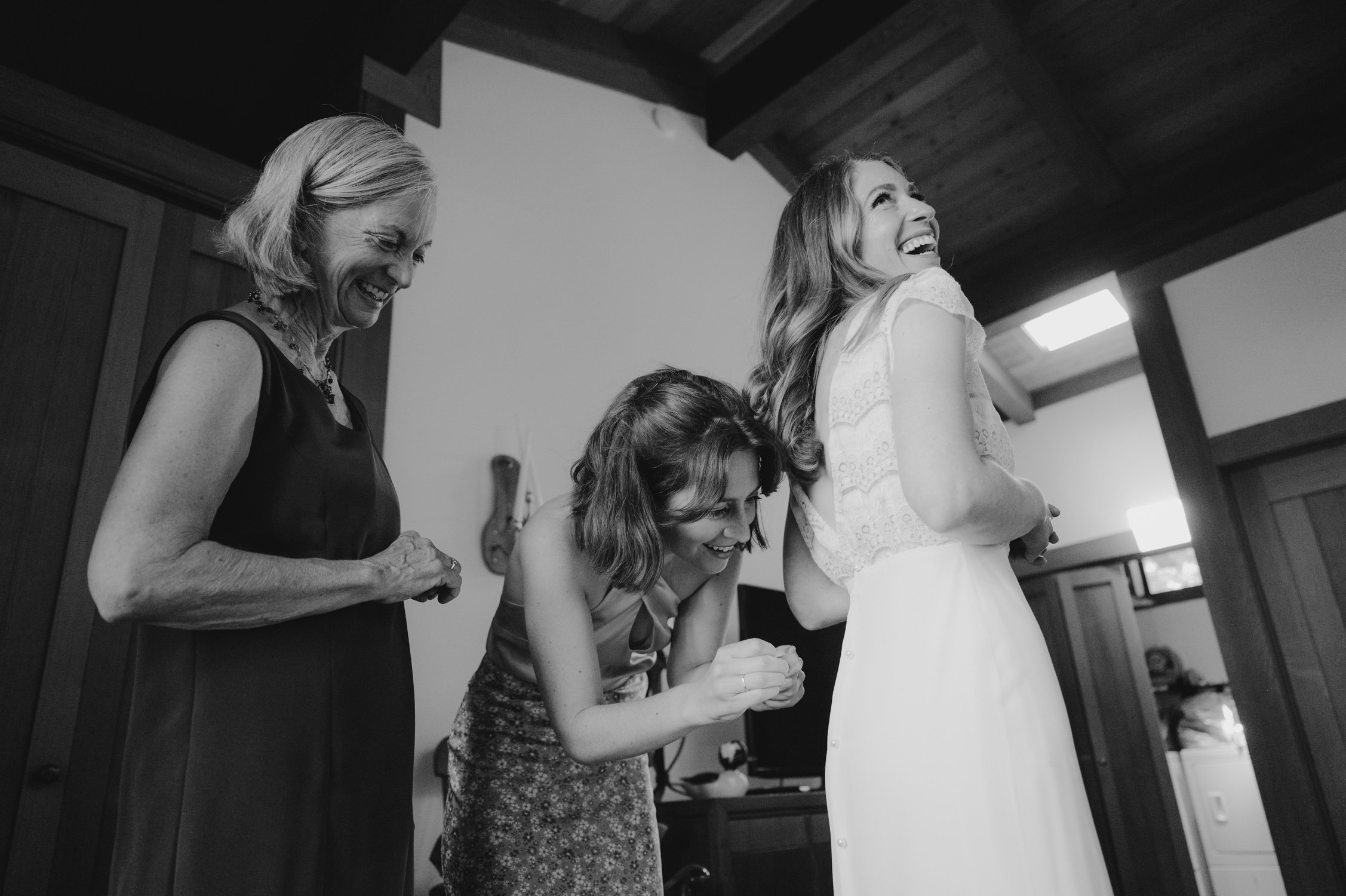 West Shore Private Estate Wedding, photo of mom and sister helping bride put on her wedding dress