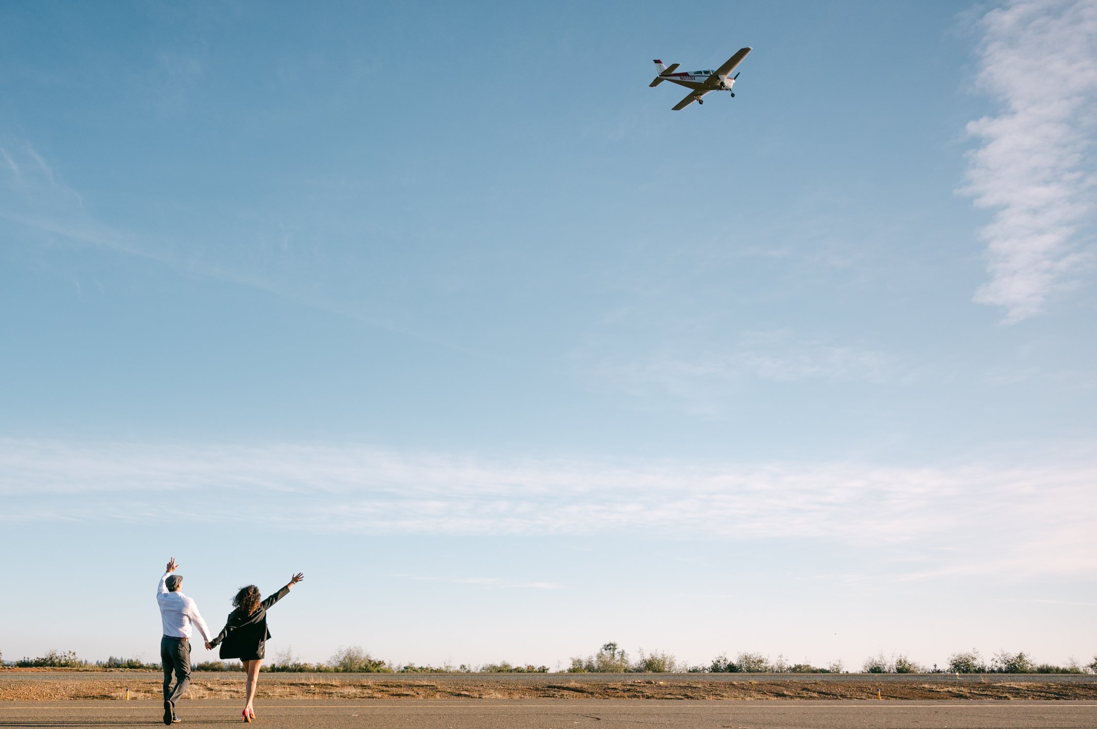 Airport photoshoot, photo of a couple with a plane in the air. 