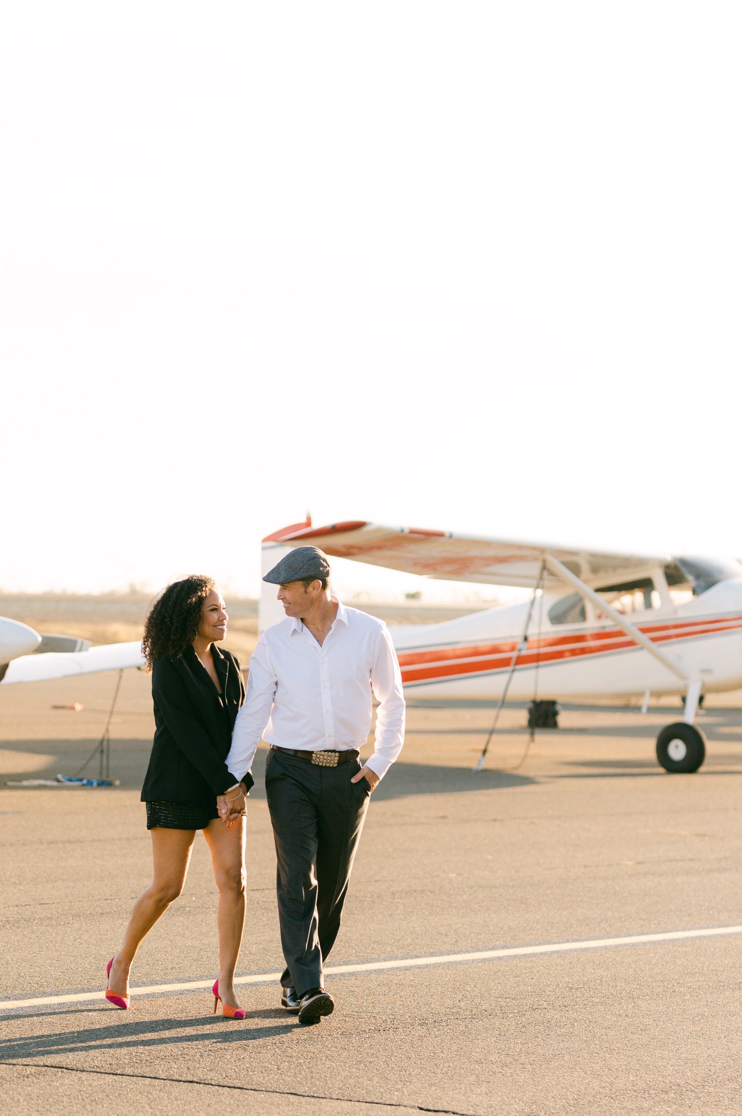 Airport photoshoot, photo of a couple walking alongside a lot of planes