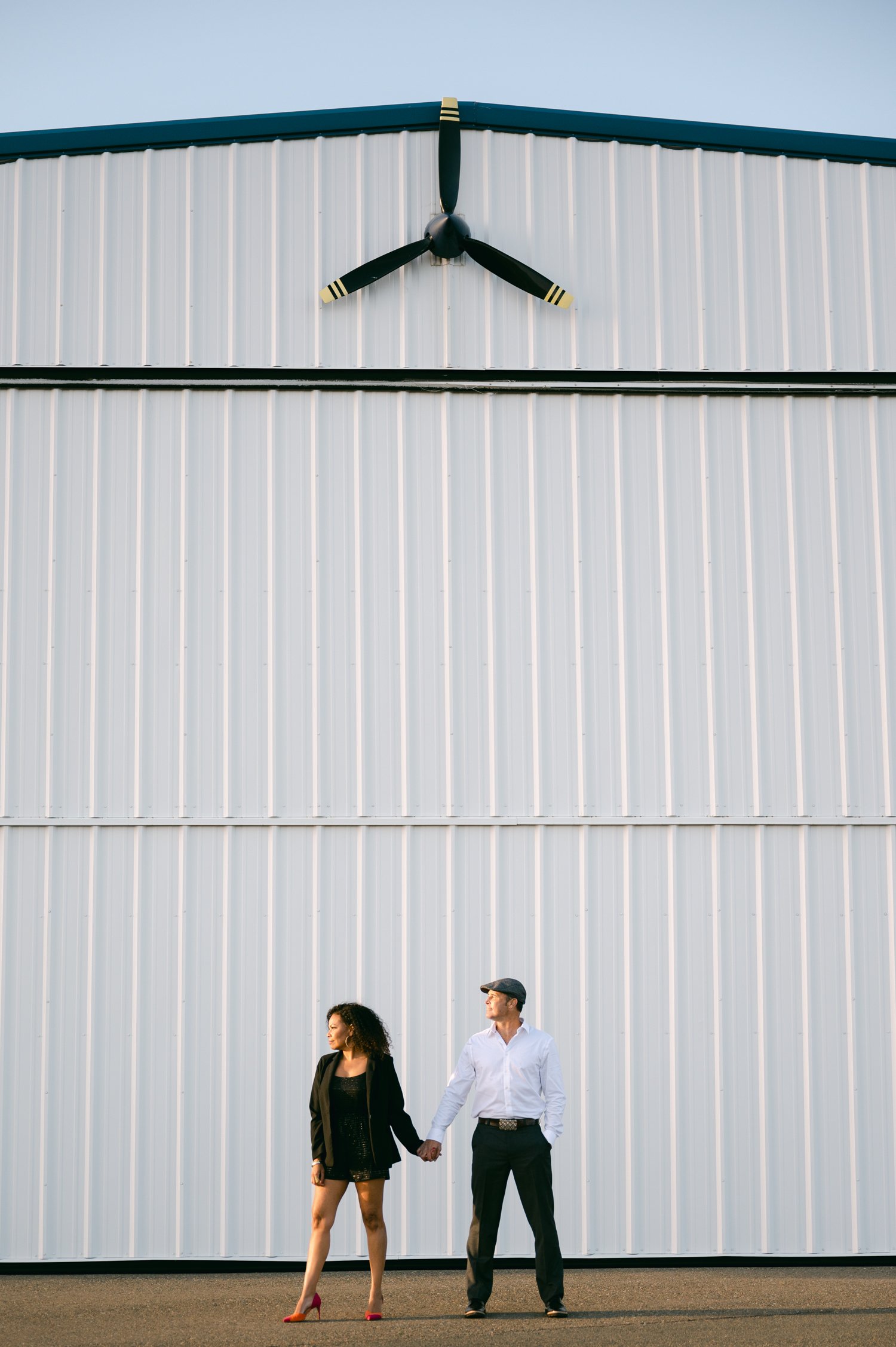 Airport photoshoot, photo of a couple standing by the airplane garage 