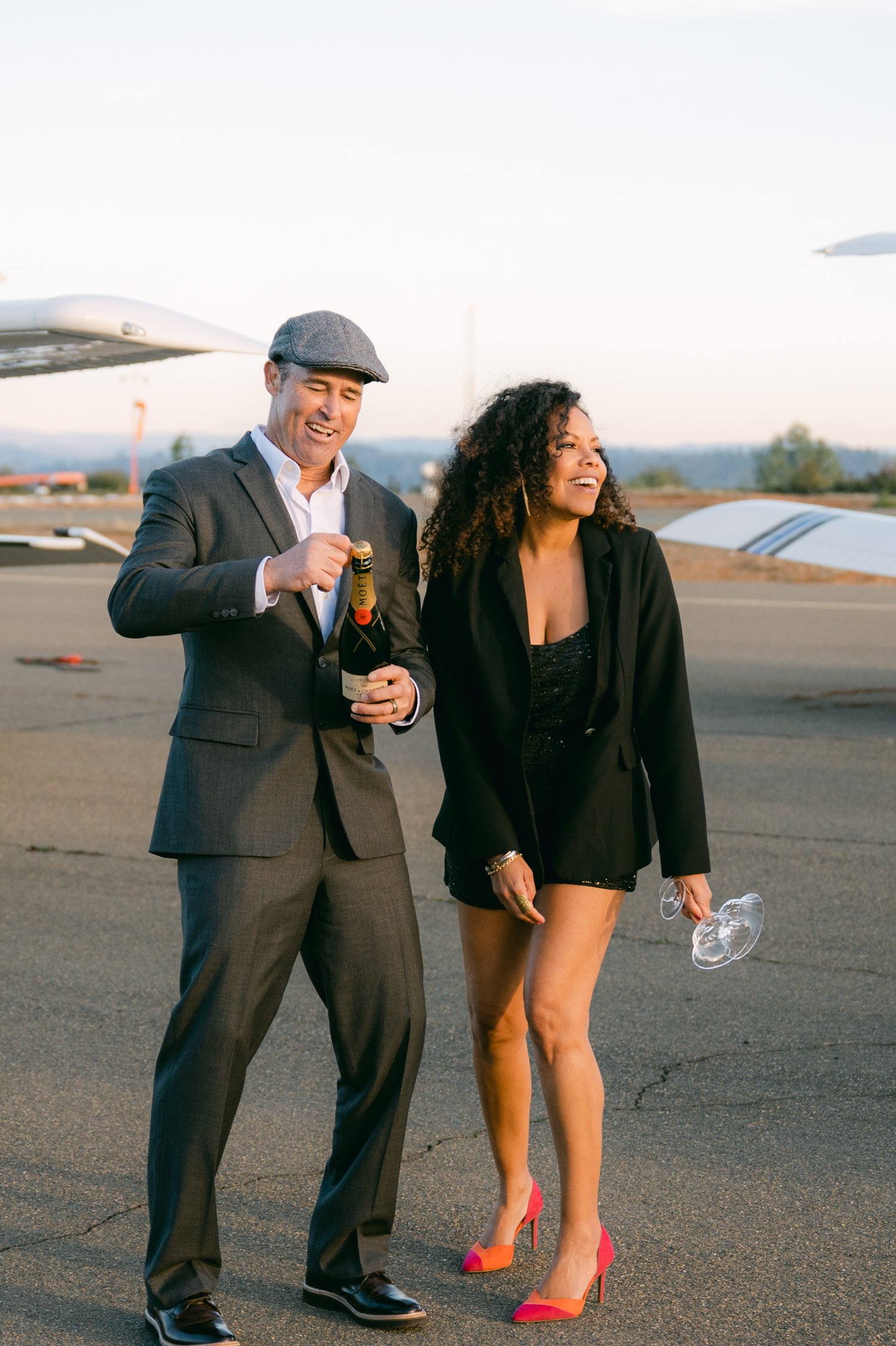 Airport photoshoot, photo of a couple popping champagne at sunset 