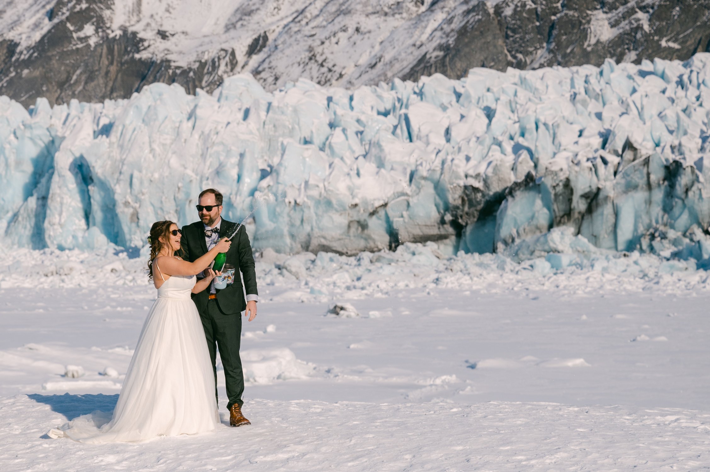 Girdwood Alaska helicopter elopement, photo of a couple popping champagne on a glacier